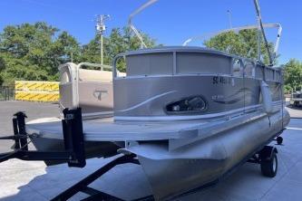 2012 Avalon Tahoe pontoon boat on trailer, parked outdoors with trees in background.