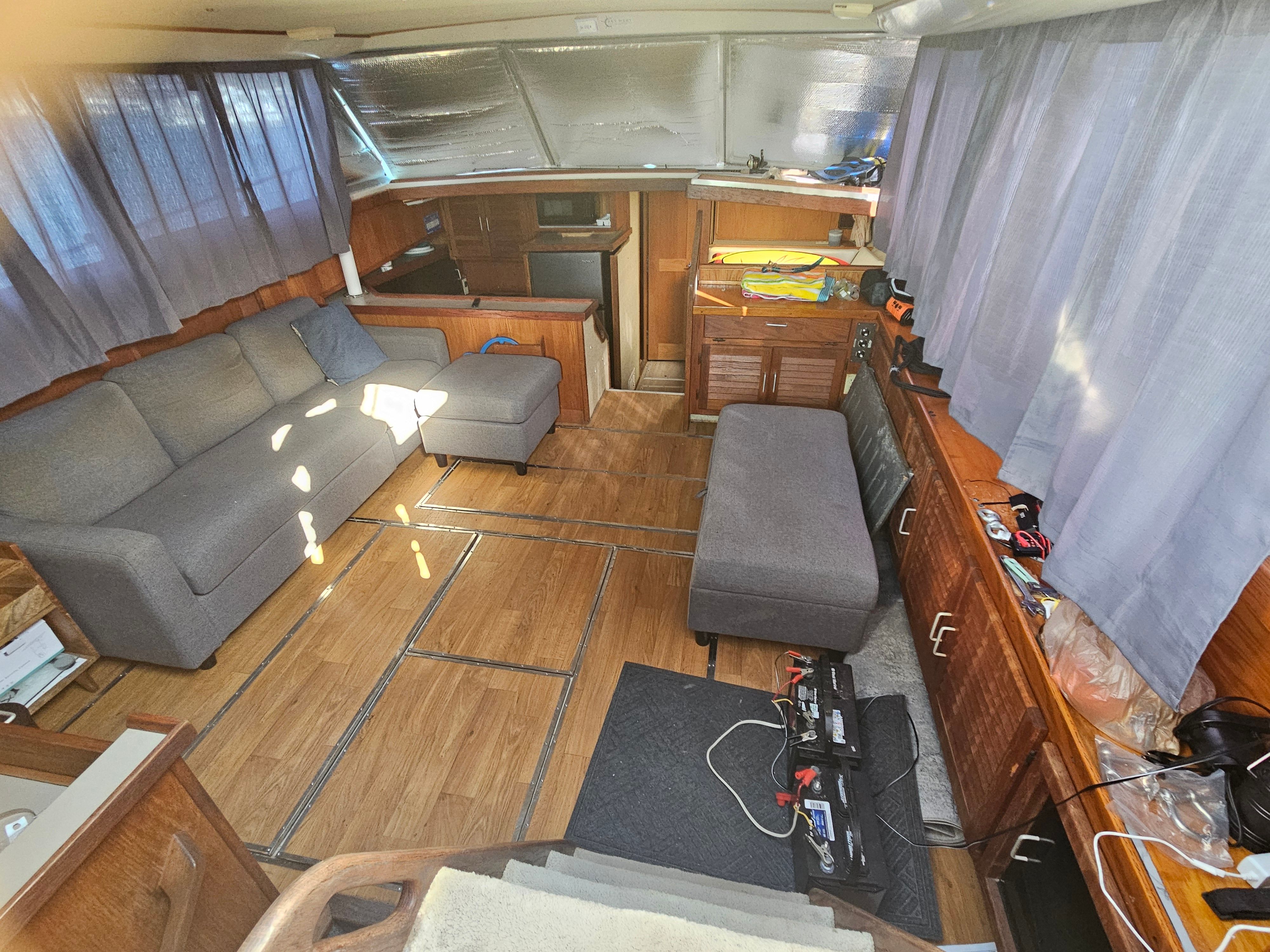 Interior of a 1984 Silverton 40 motor yacht with gray sofa and wooden flooring.