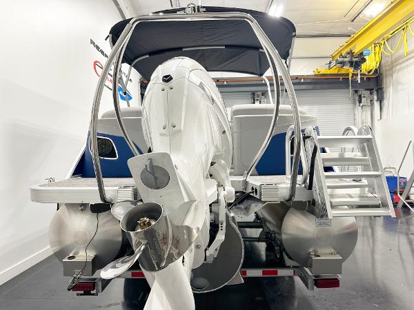 2025 Bennington 23LFBCSR pontoon boat in a garage, rear view with motor and ladder.