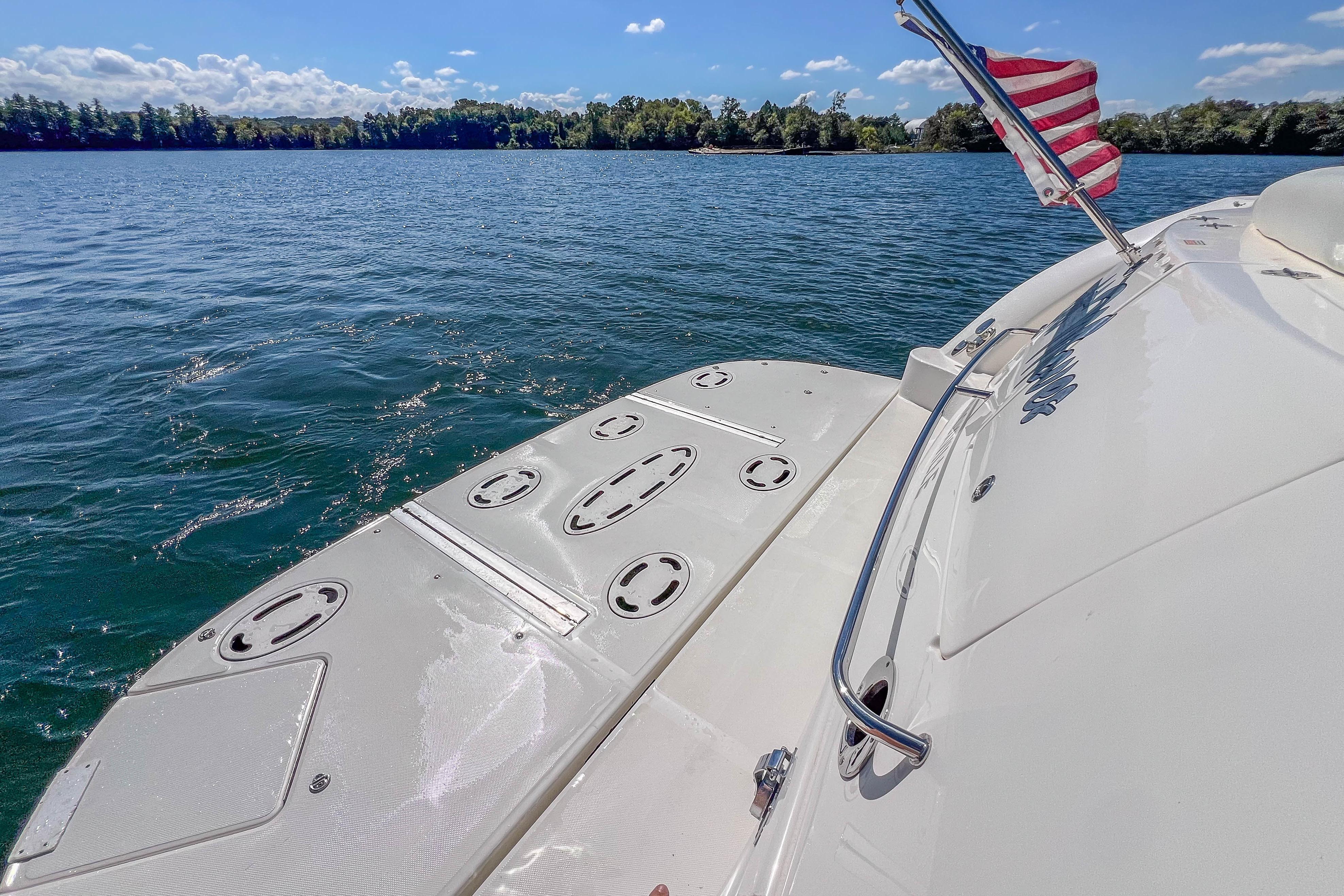 2005 Sea Ray 500 Sundancer yacht on serene lake with American flag.