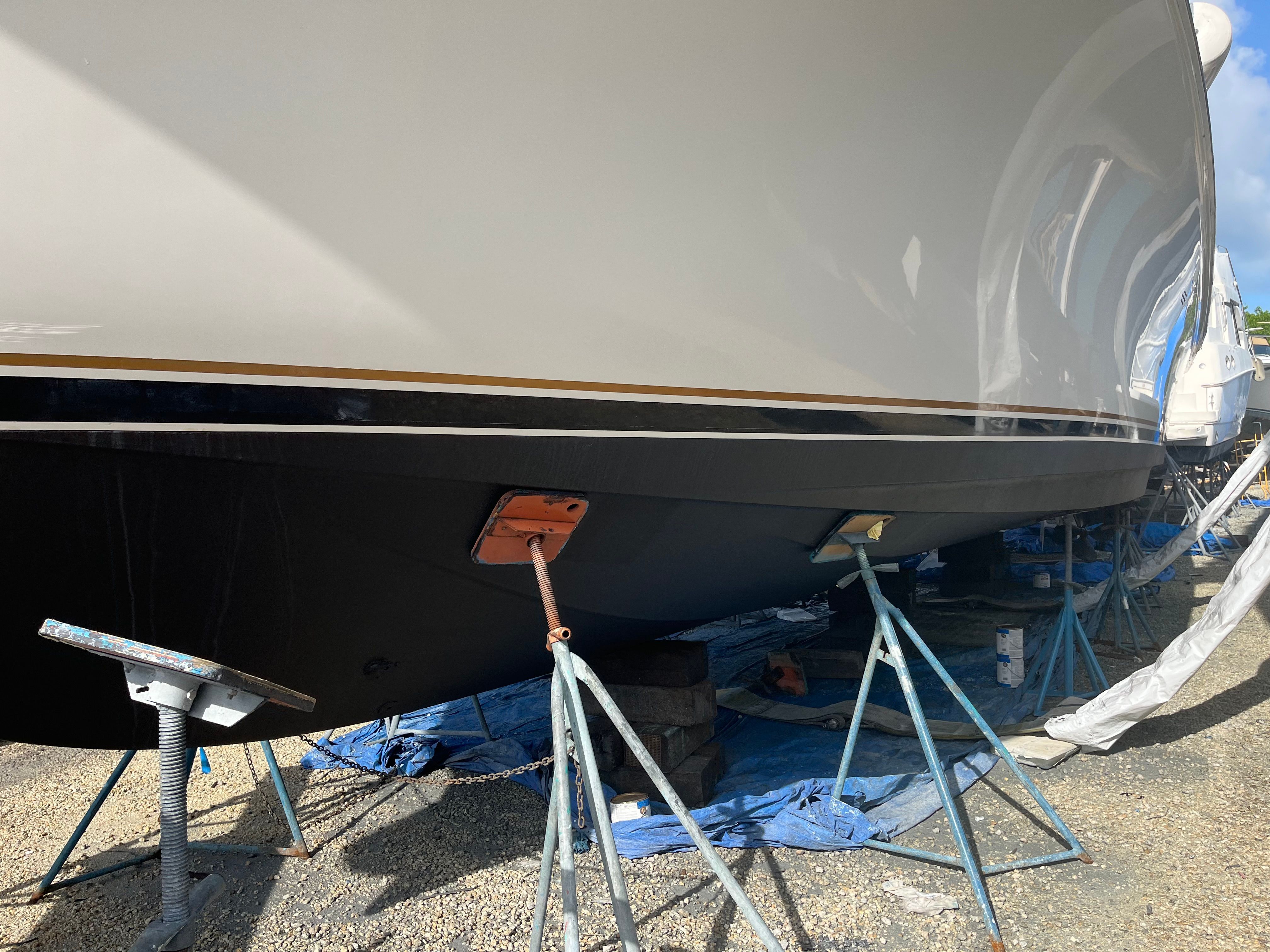A 2002 Ocean Yachts 48 Super Sport is on stands on land, with blue tarp underneath.