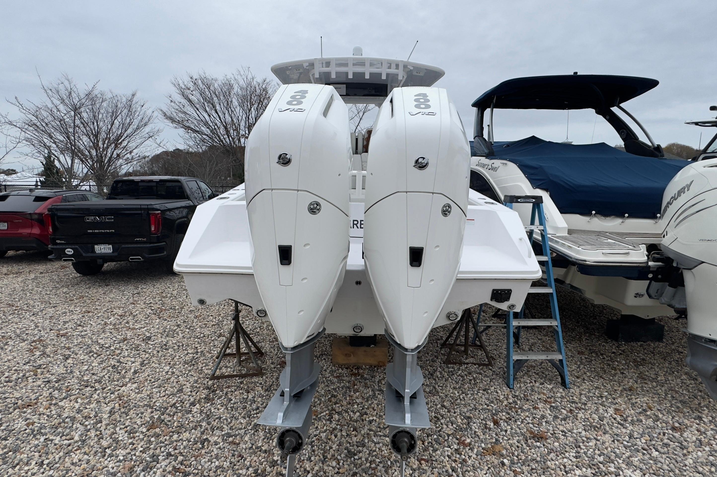 2024 Jupiter 32 FS boat with dual outboard engines on gravel lot.