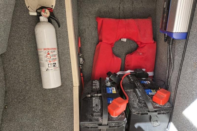 Storage compartment of a 2007 Grady-White Tournament 205 with batteries, fire extinguisher, and life jacket.