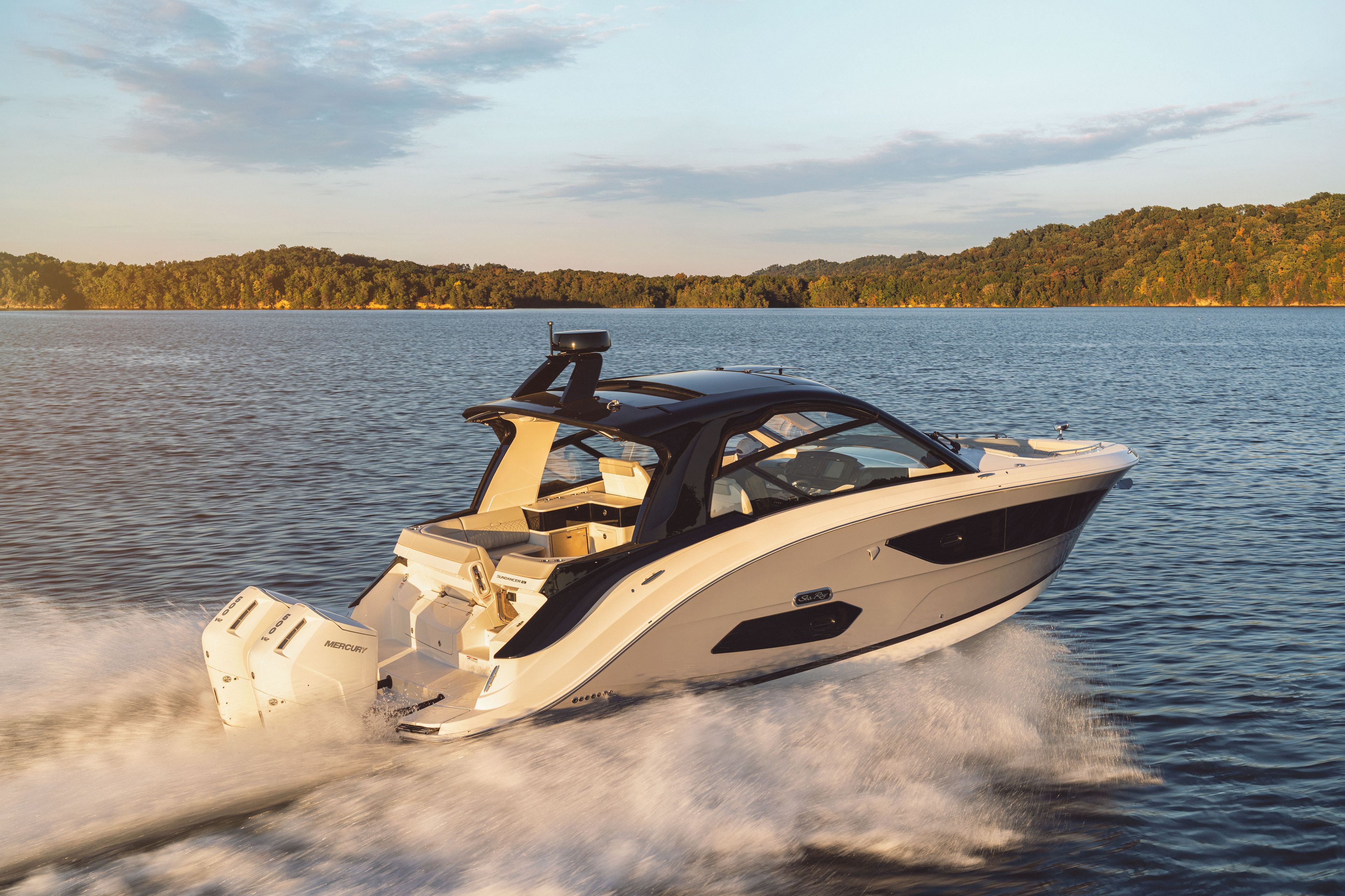 Sea Ray Sundancer 370 Outboard cruising swiftly on a calm lake at sunset.