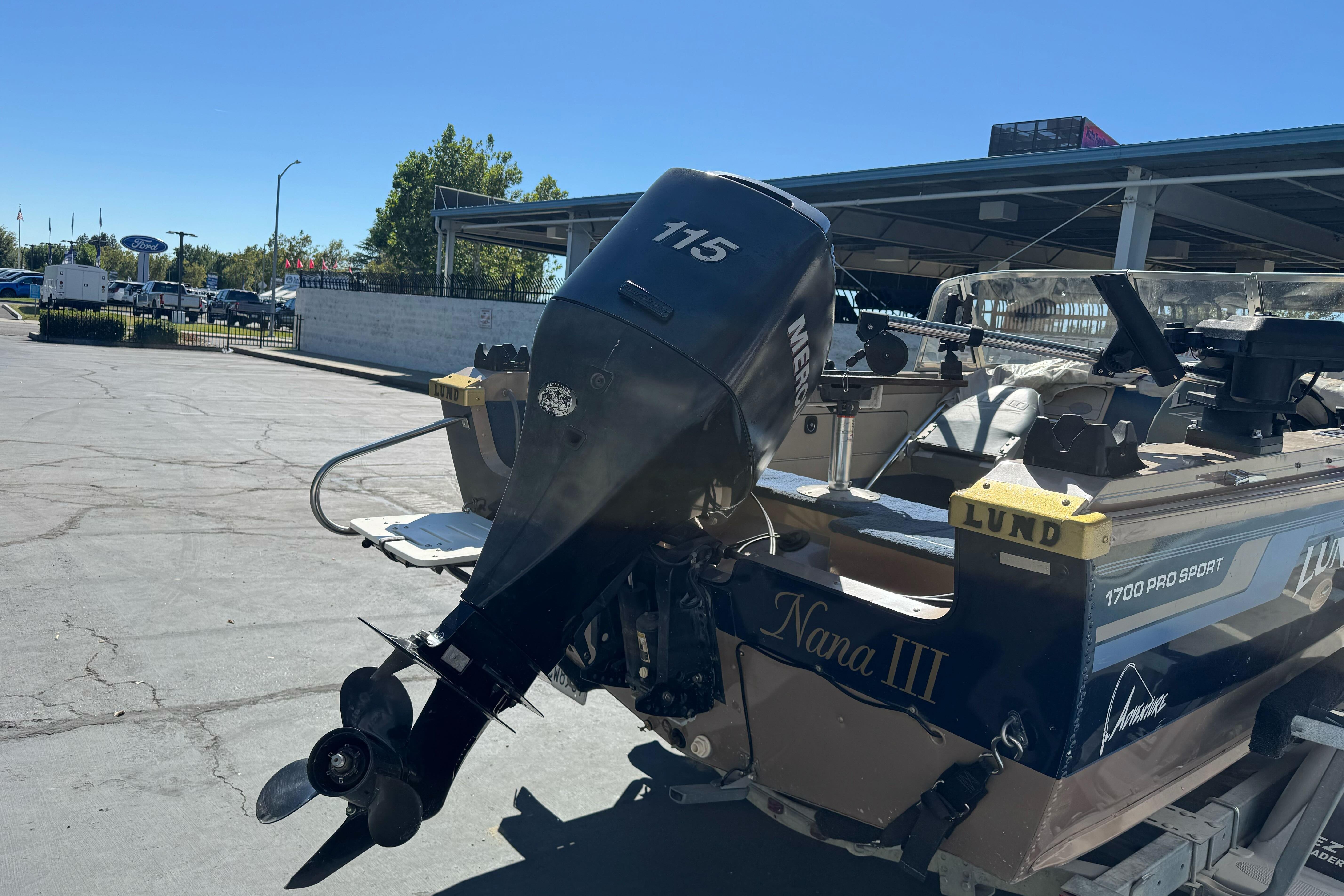 1998 Lund 1700 Pro Sport boat with Mercury 115 outboard motor in parking lot.