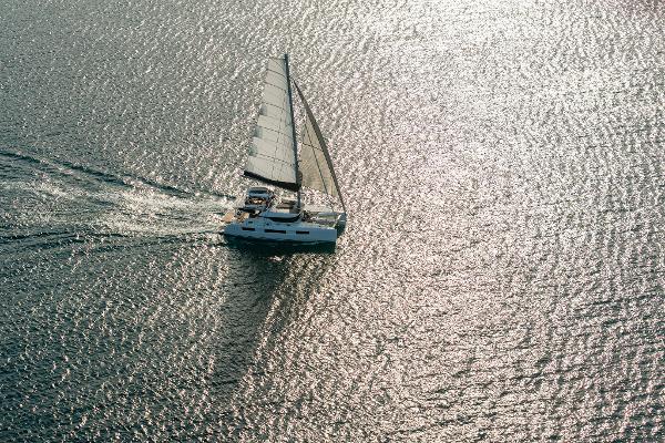 Aerial view of 2025 Lagoon 51 ICONIC sailing on shimmering water.