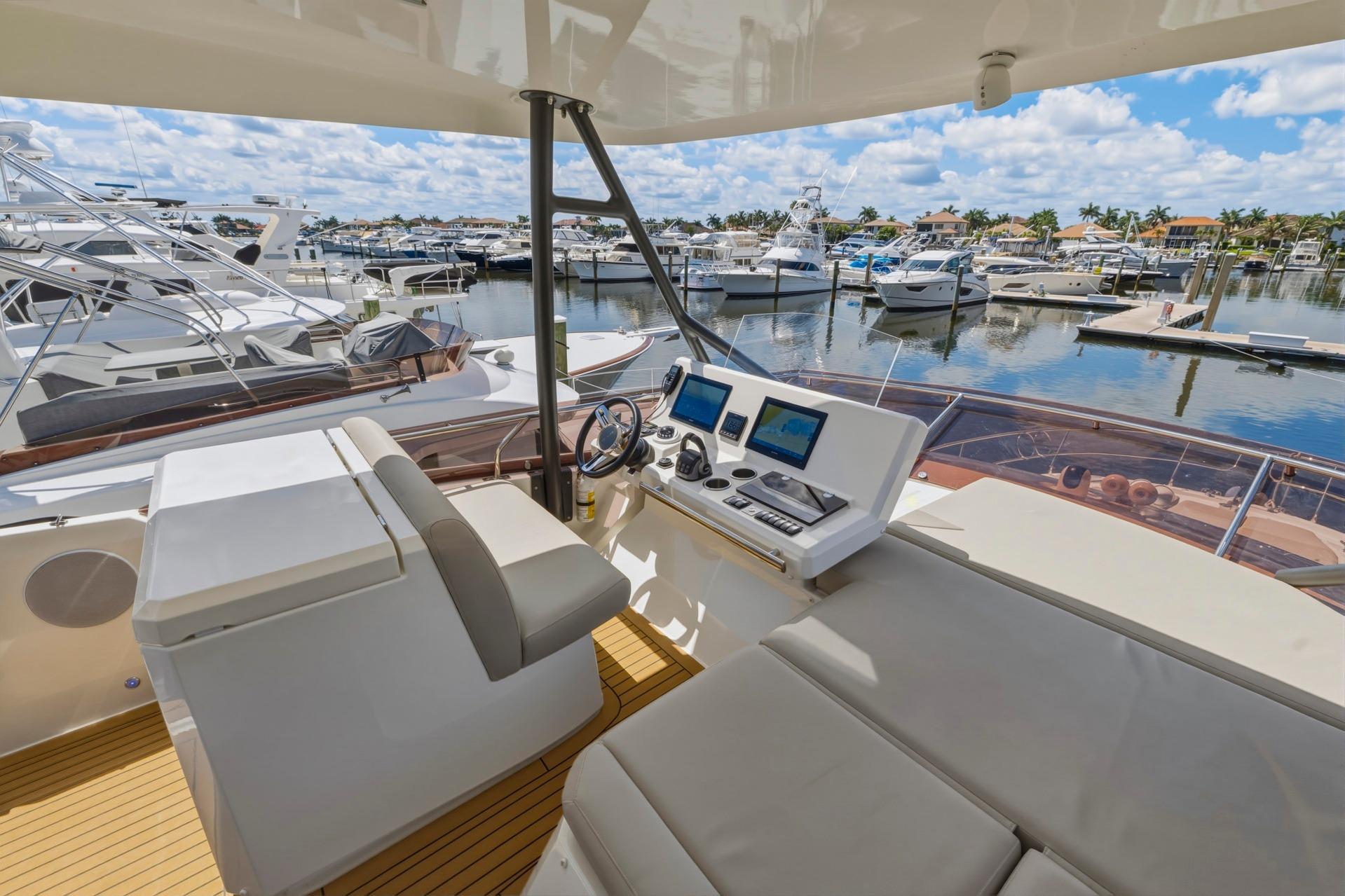 Luxurious 2022 Prestige 520 yacht interior with modern helm, docked at a scenic marina.