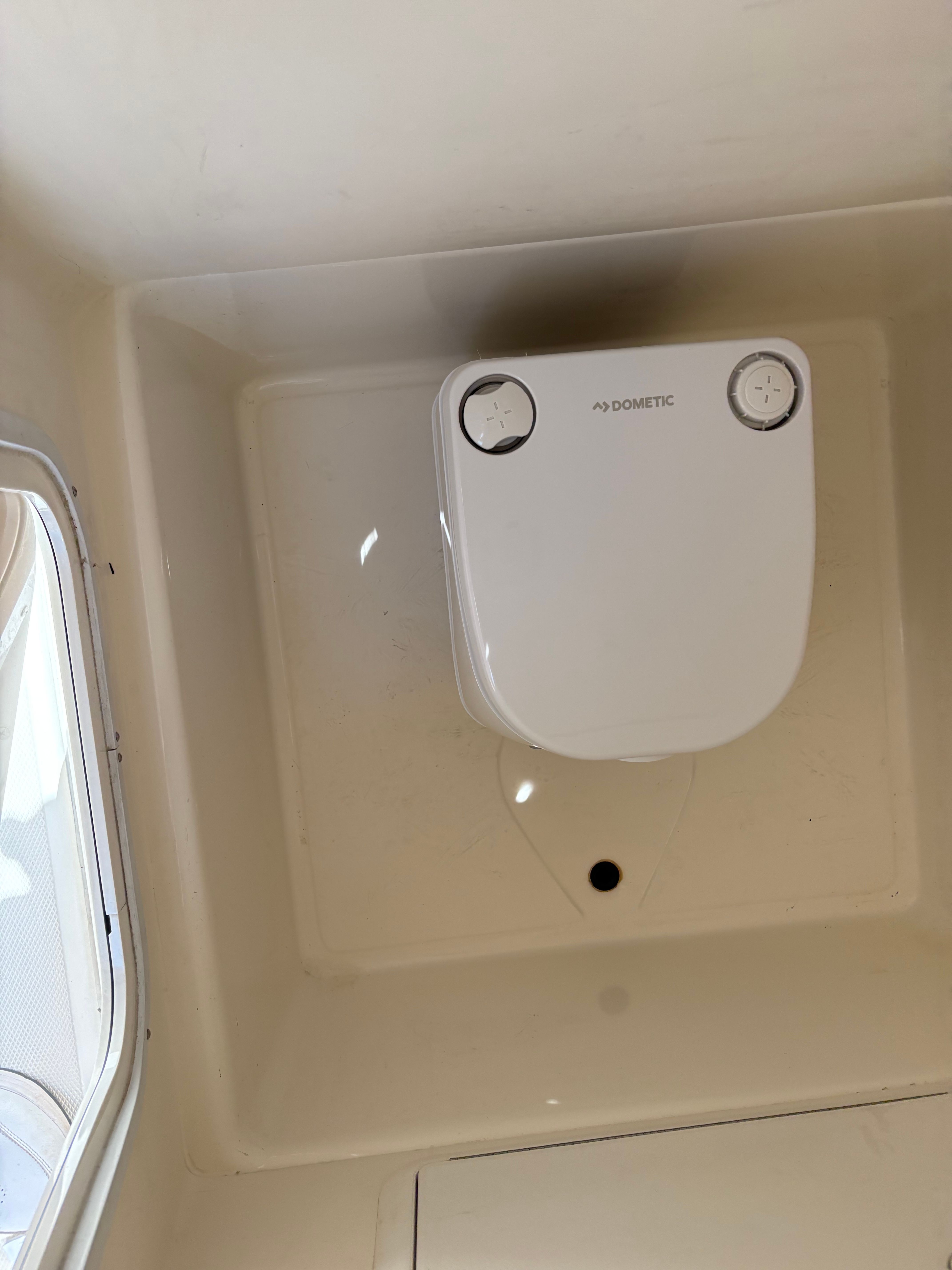 Interior of a boat with a Dometic toilet and a window.