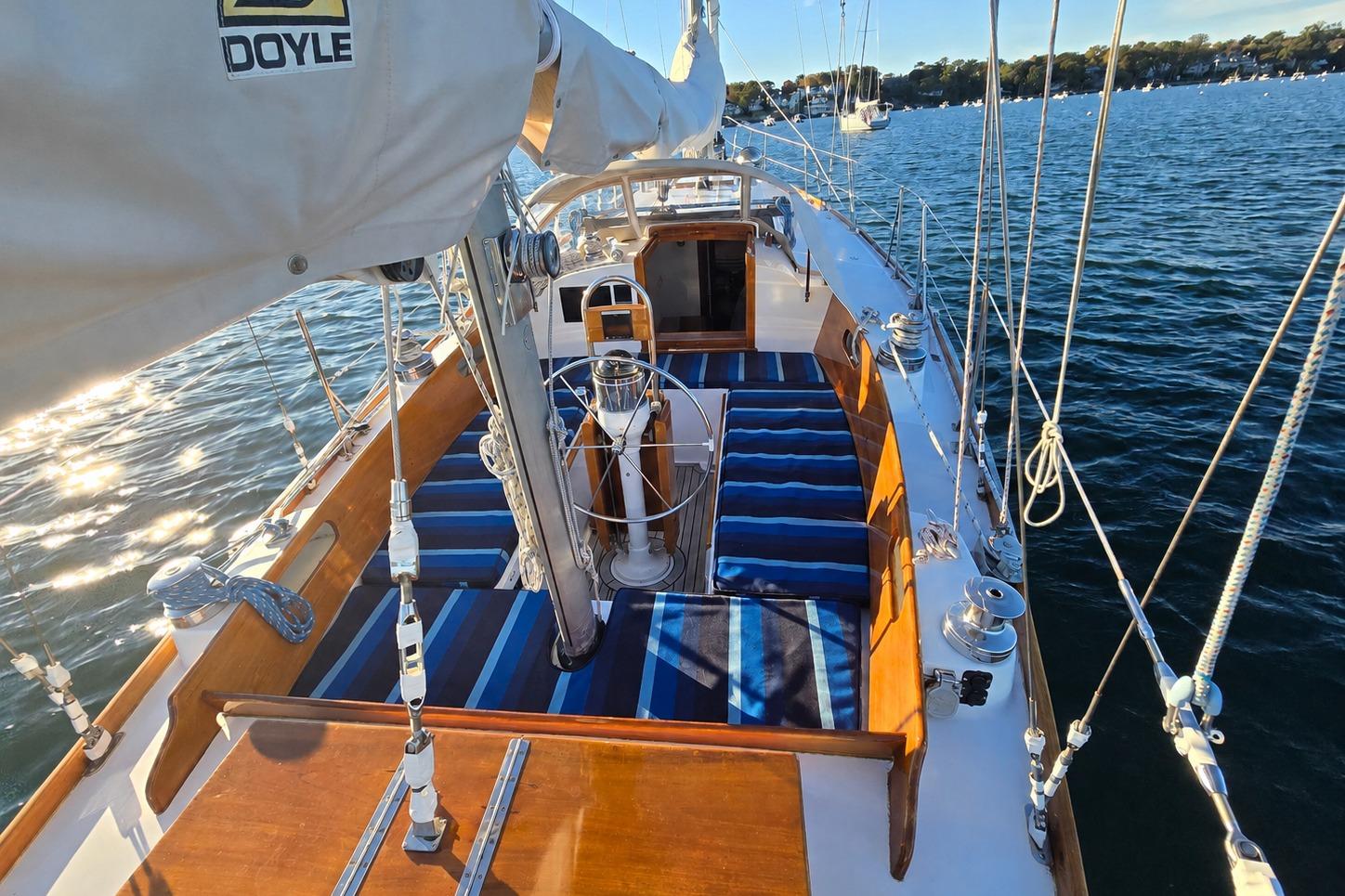 1970 Hinckley Bermuda 40 sailboat with striped cushions on deck, sailing on calm waters.