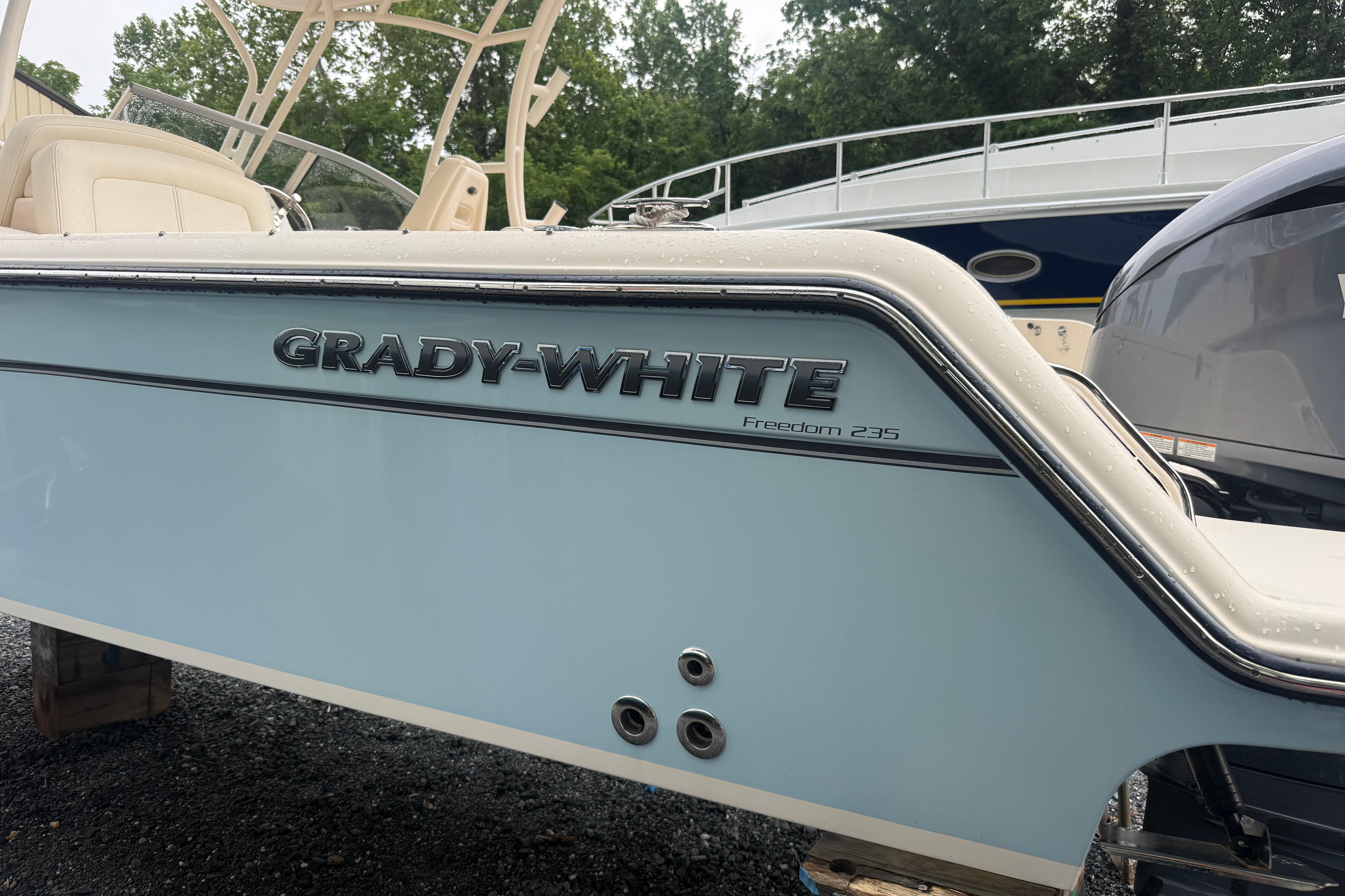 2022 Grady-White Freedom 235 boat, side view with logo, parked outdoors.