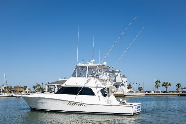 1999 Viking 47 Convertible yacht docked in a marina under clear blue skies.