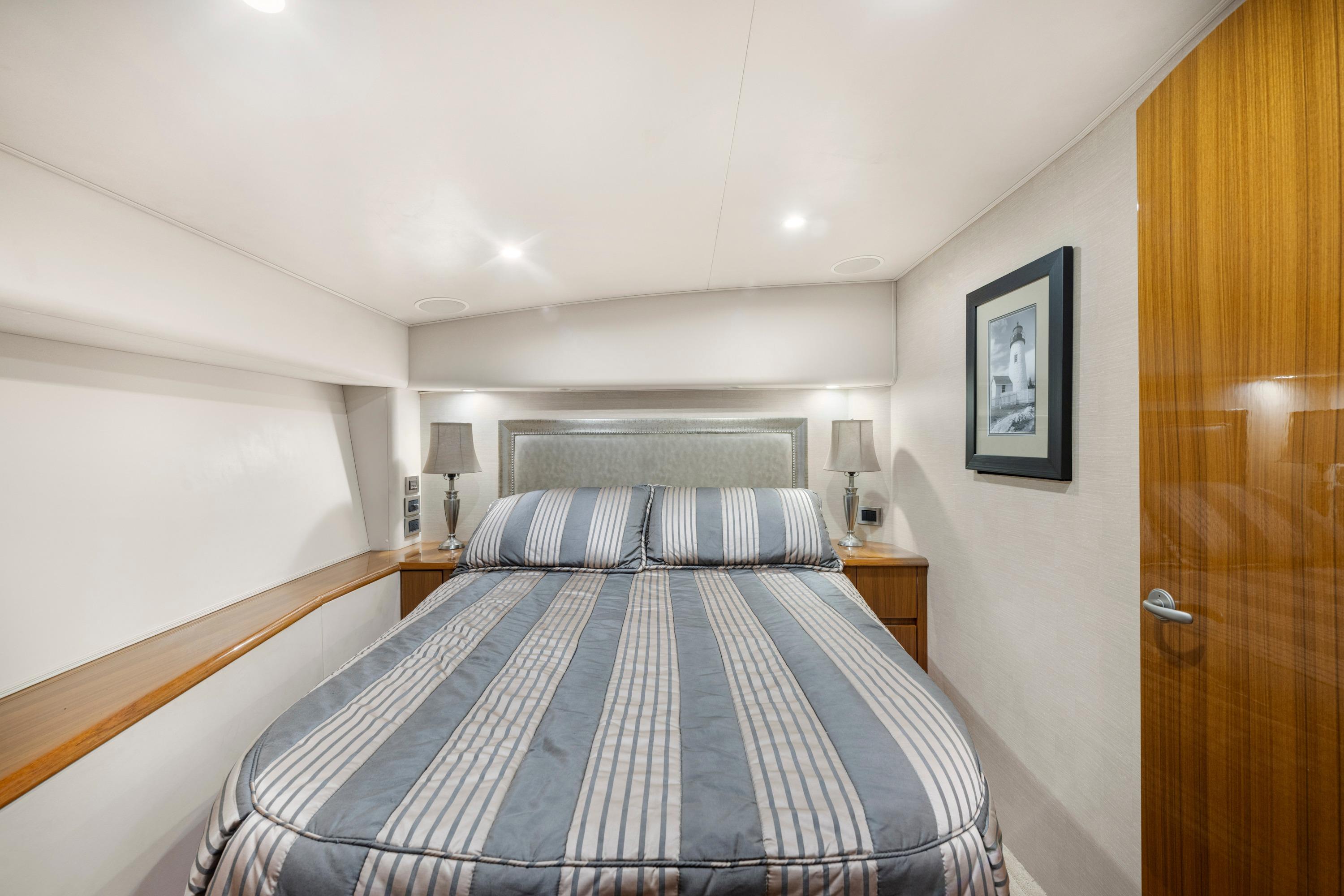 Luxurious bedroom interior of 2009 Viking 50 Convertible yacht with striped bedding and elegant decor.