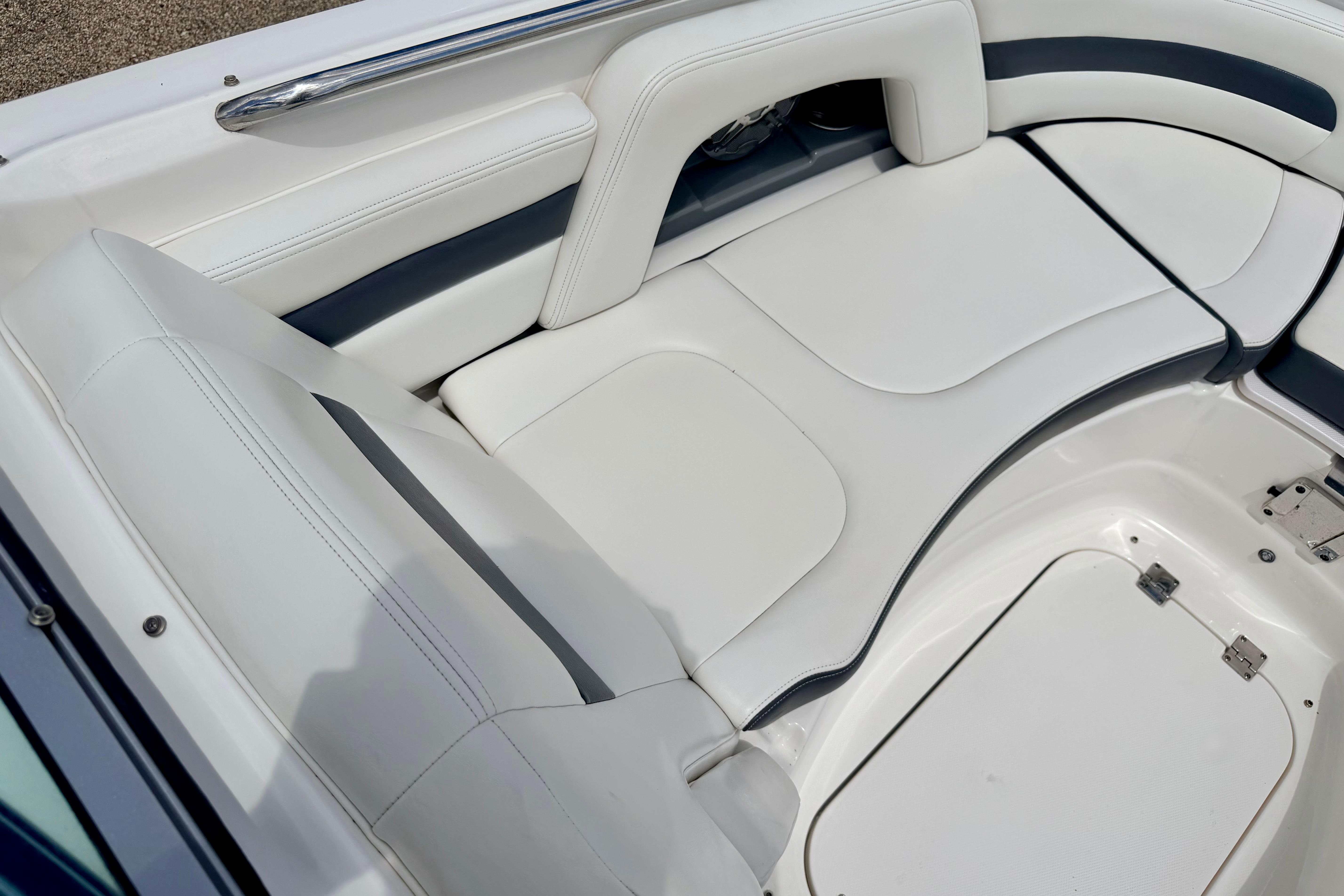 2015 Chaparral Sunesta 264 boat interior with white cushioned seating and storage compartments.