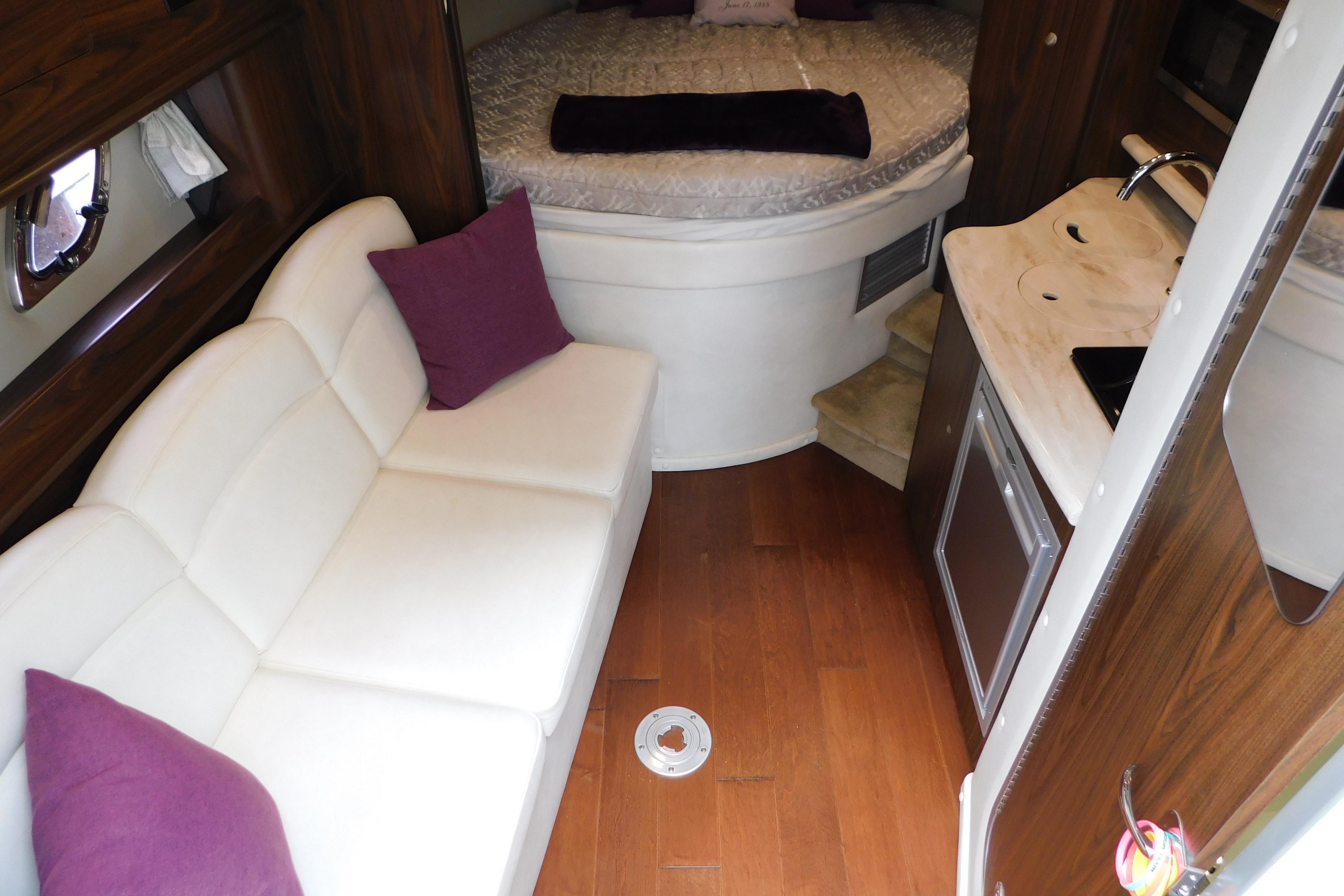 Interior of 2017 Rinker EX 320 boat with white sofa, bed, and kitchenette.