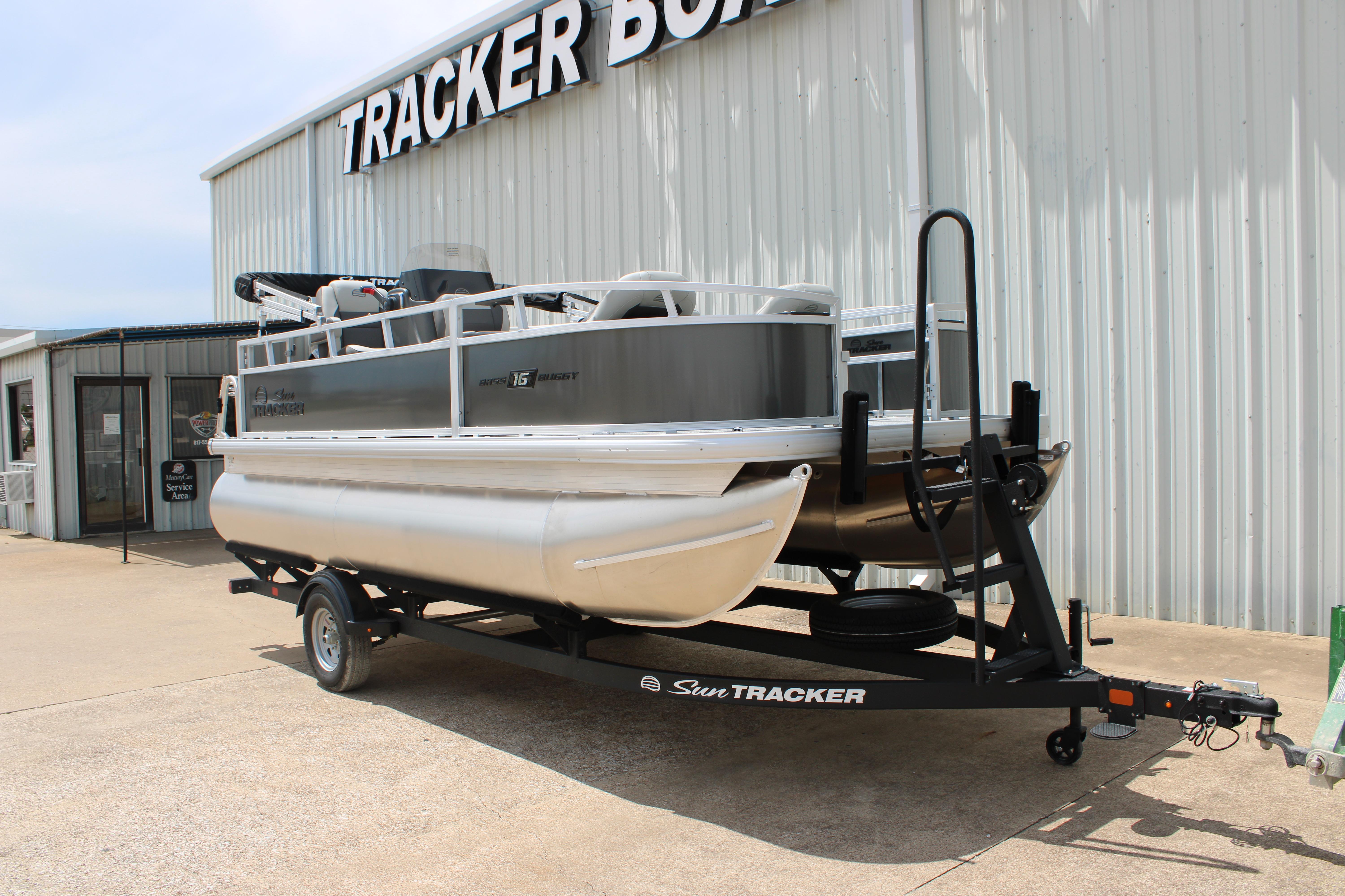 2026 Sun Tracker Bass Buggy 18 DLX pontoon boat on trailer outside dealership.