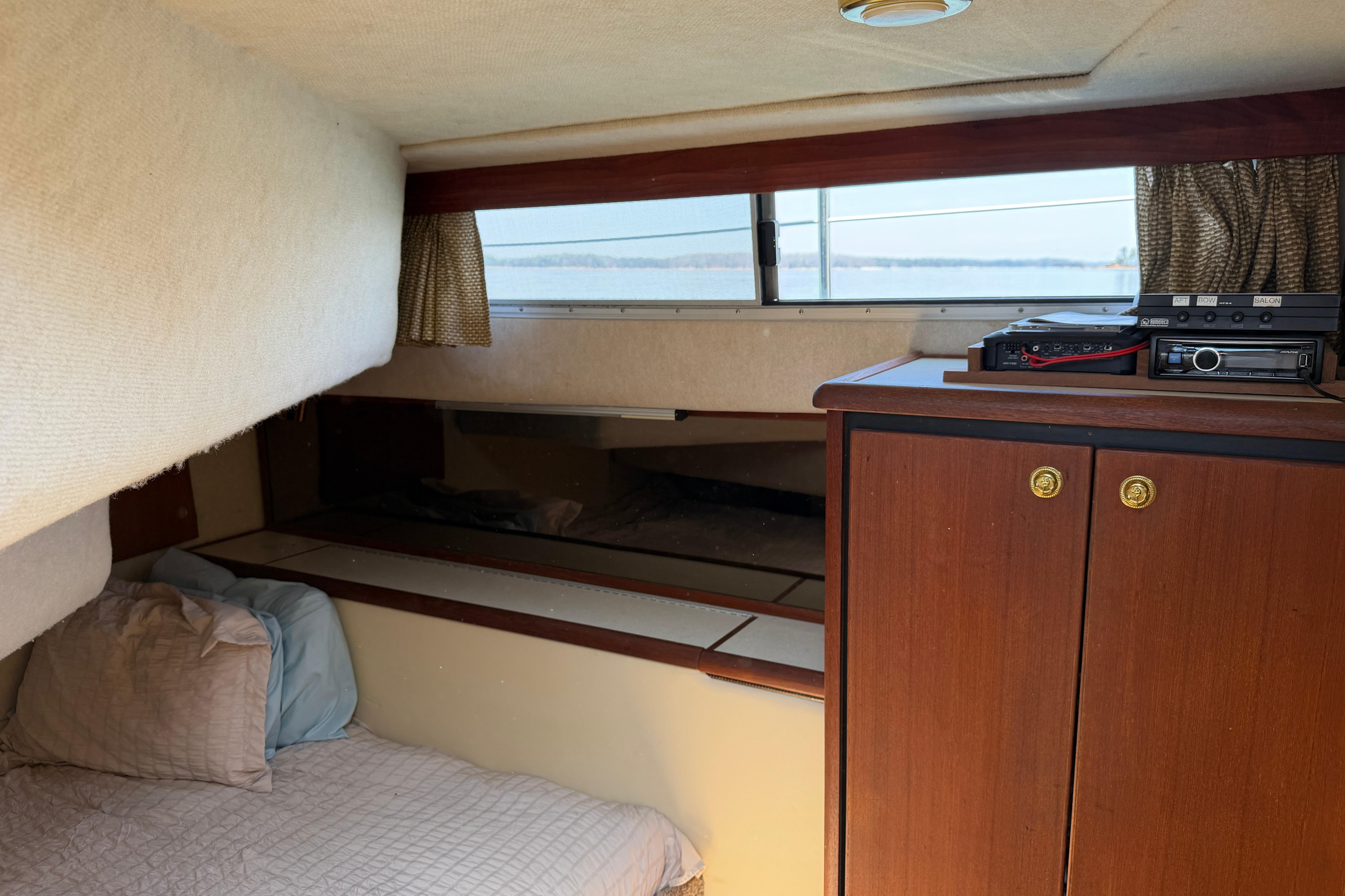 Cozy cabin interior of 1994 Bayliner 3888 MY Sedan with bed and wooden cabinetry.