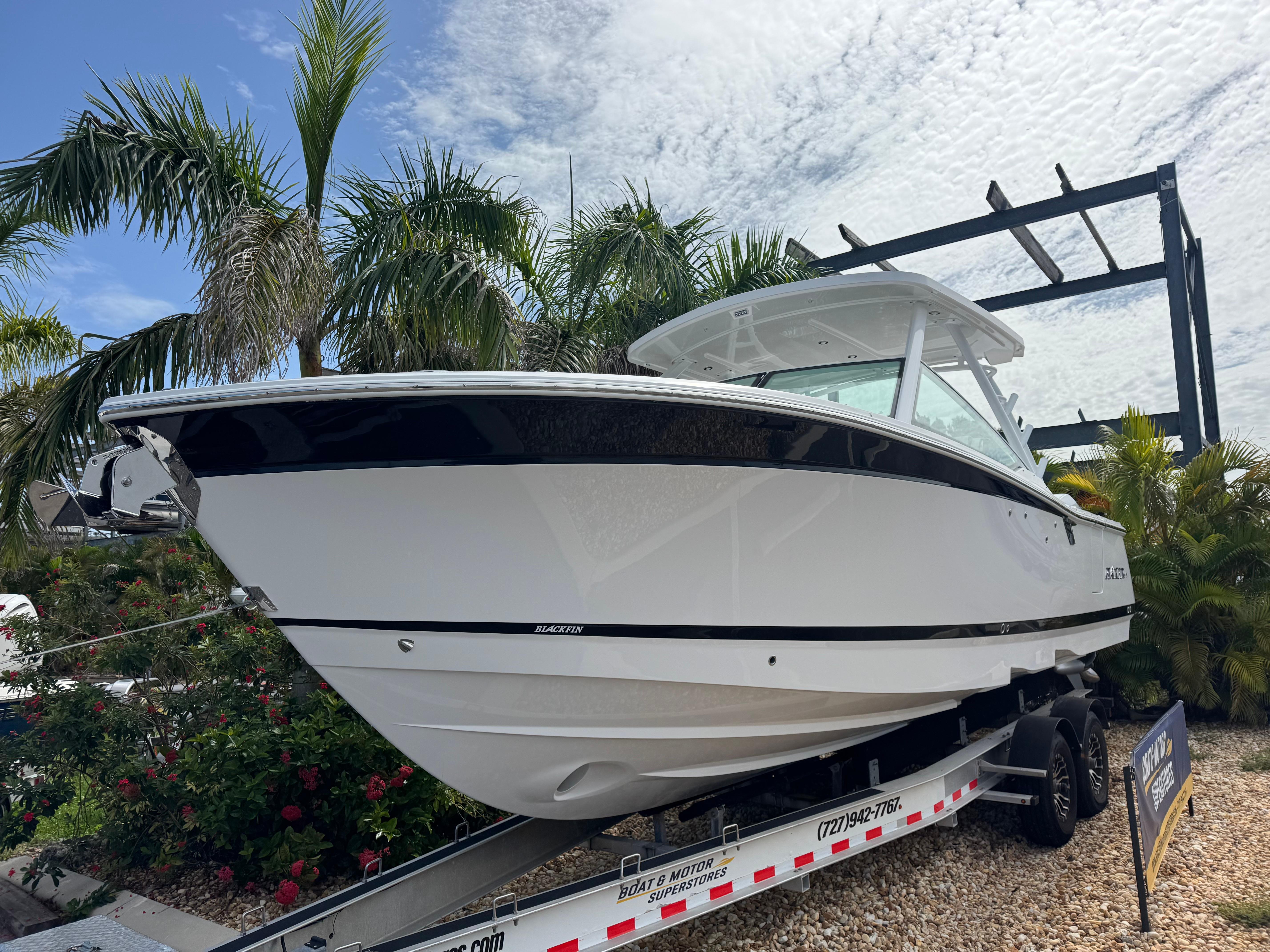 2026 Blackfin 302 DC boat on trailer, surrounded by palm trees and a cloudy sky.