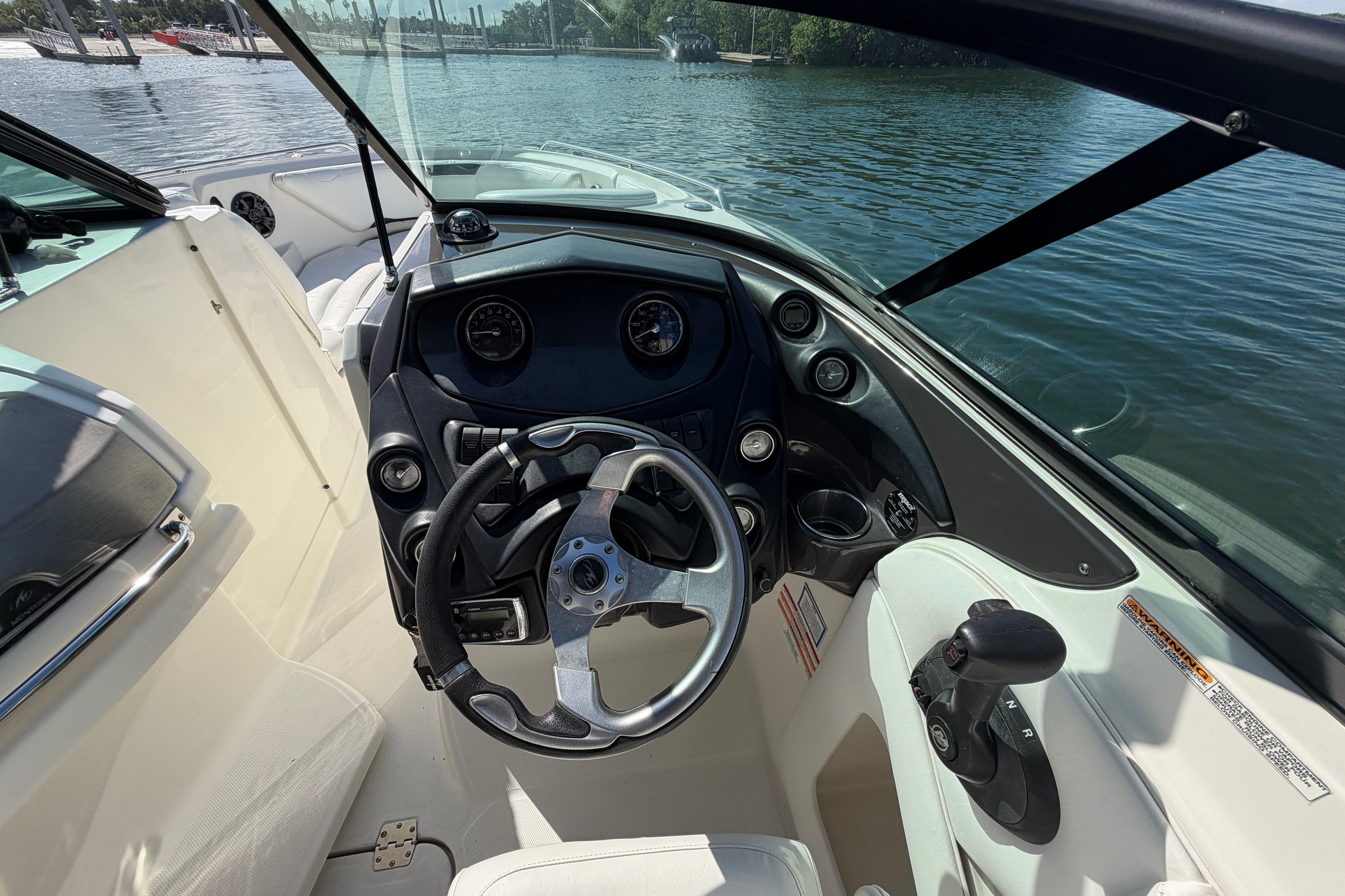 2015 Monterey 264FS boat cockpit with steering wheel and controls, docked by the water.