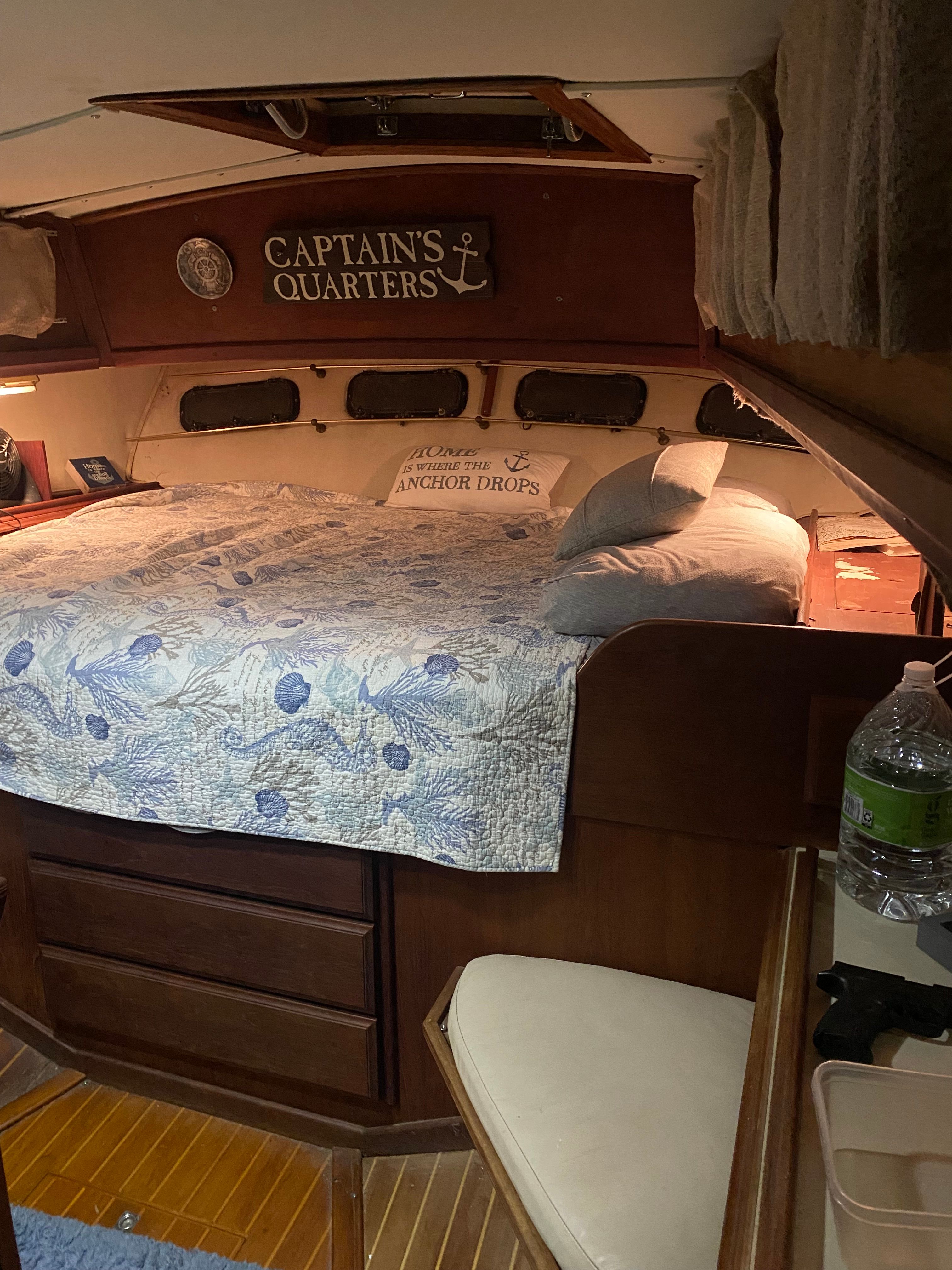 Cozy cabin with a large bed, wooden furnishings, and a sign reading "Captain's Quarters."