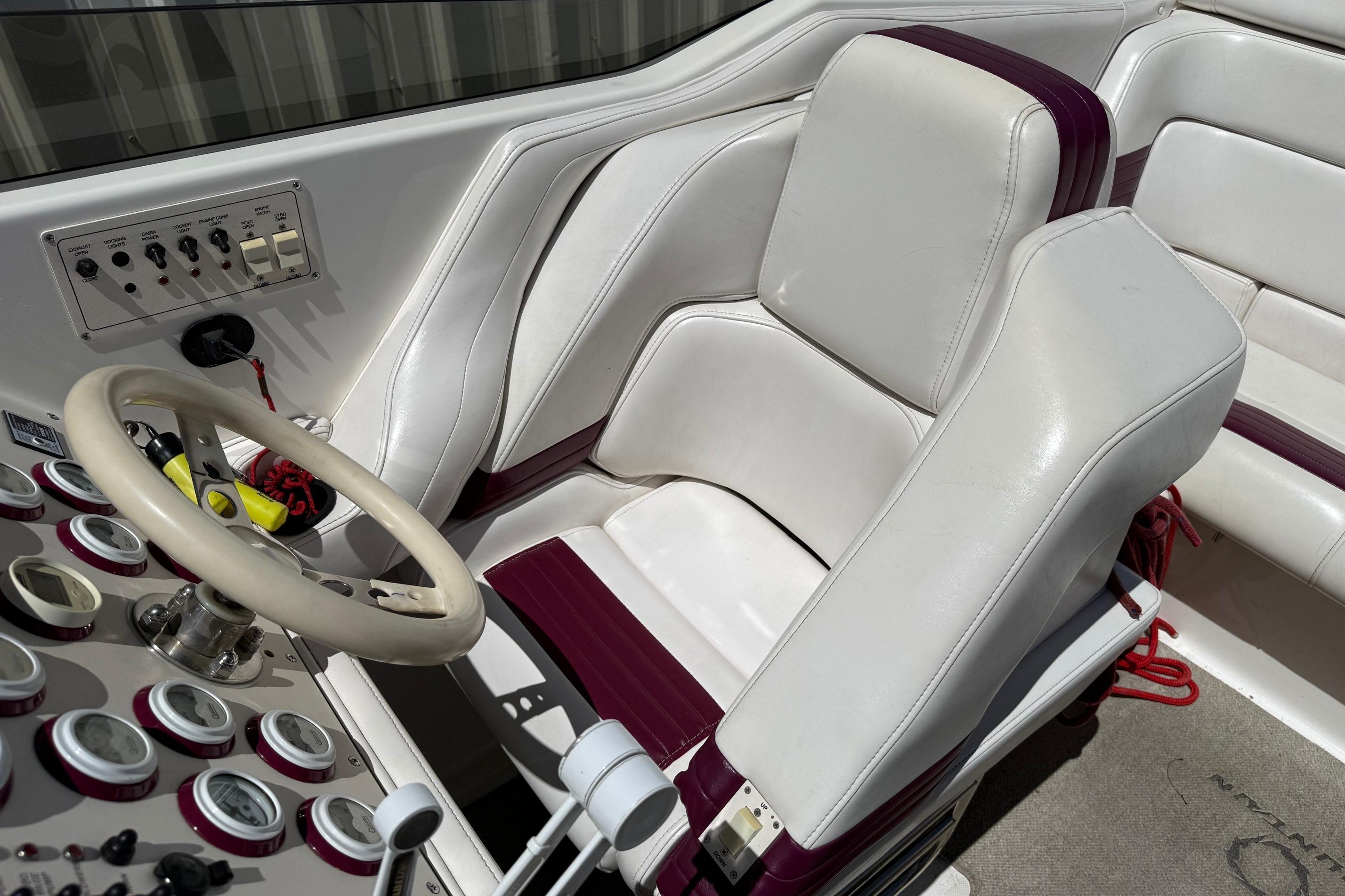 1998 Fountain 35 Lightning boat cockpit with white and maroon seating, steering wheel, and control panel.