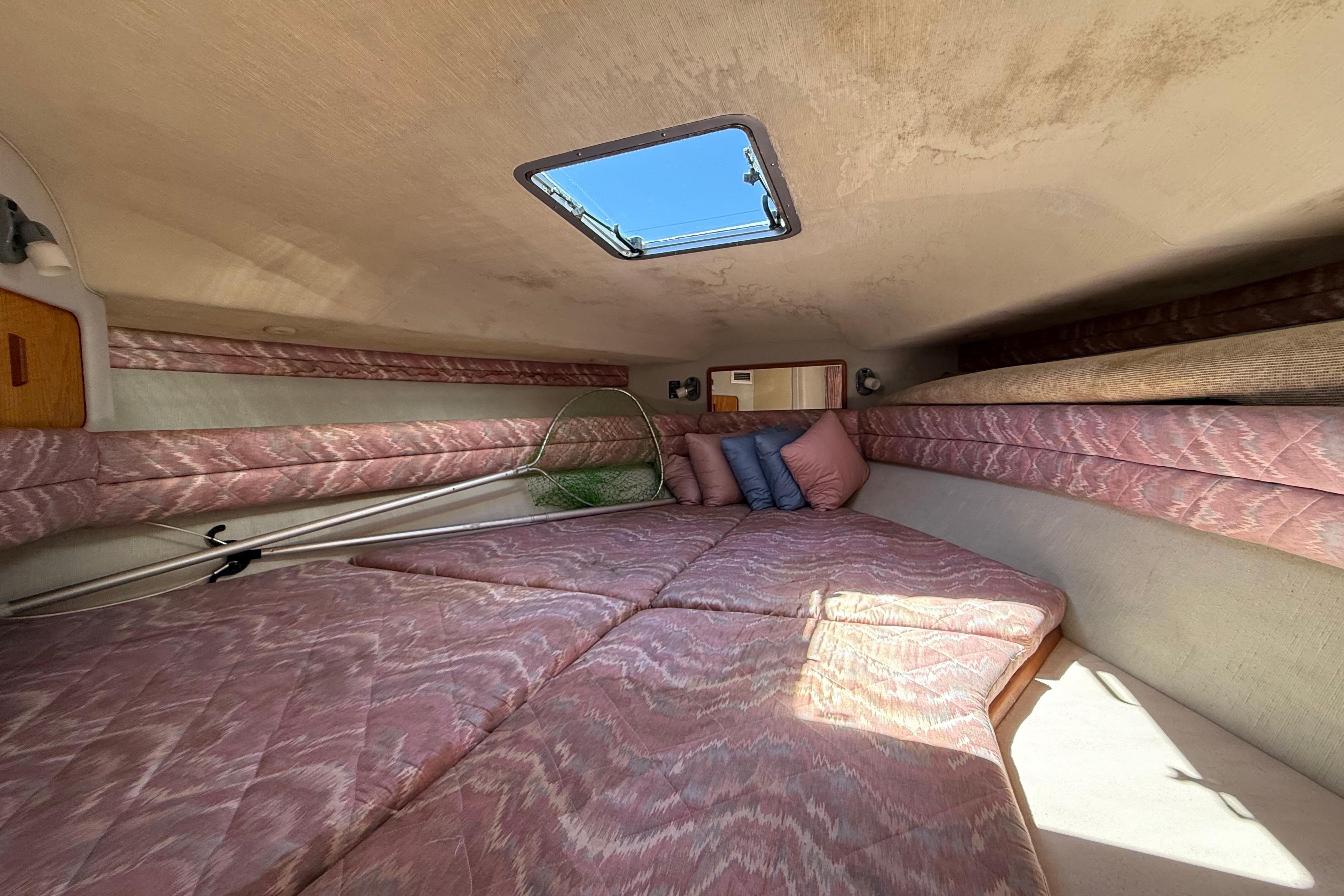 1990 Sea Ray 310 Express Cruiser cabin interior with pink bedding and skylight.