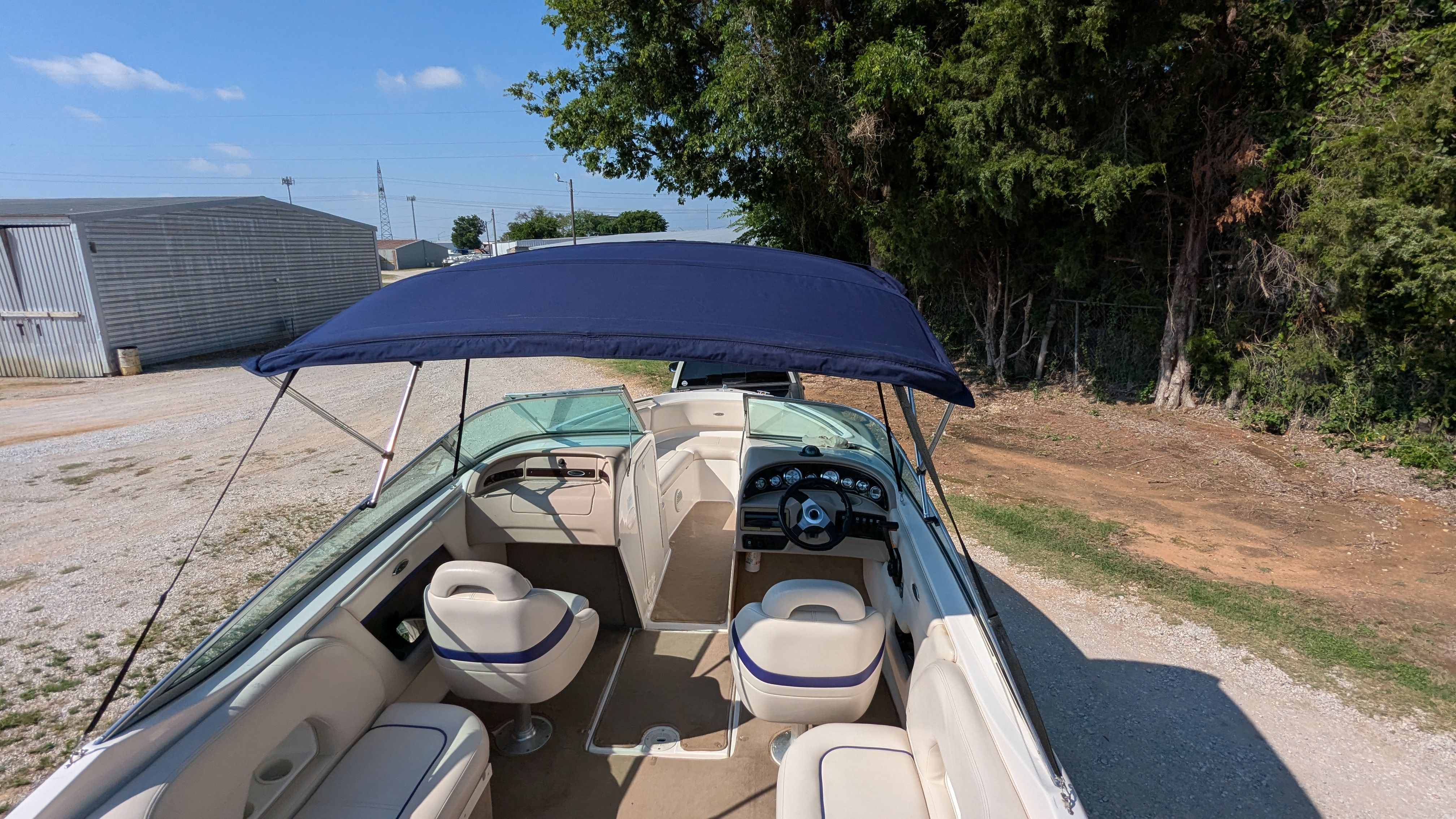 2000 Chaparral 240 SSi with open cockpit and blue Bimini top, parked on land.
