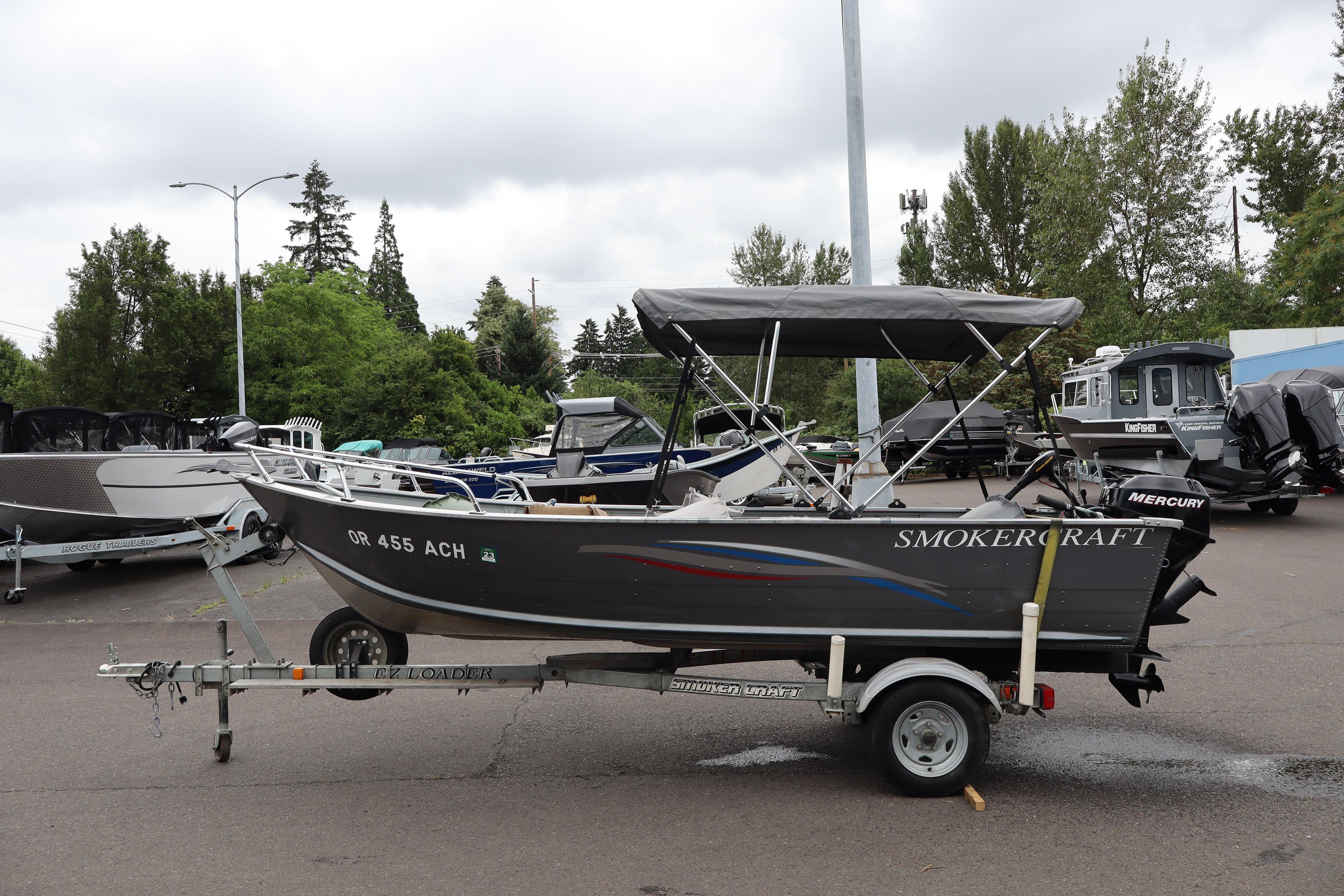 2006 Smoker Craft Alaskan 15 boat on trailer, parked outdoors with trees in background.