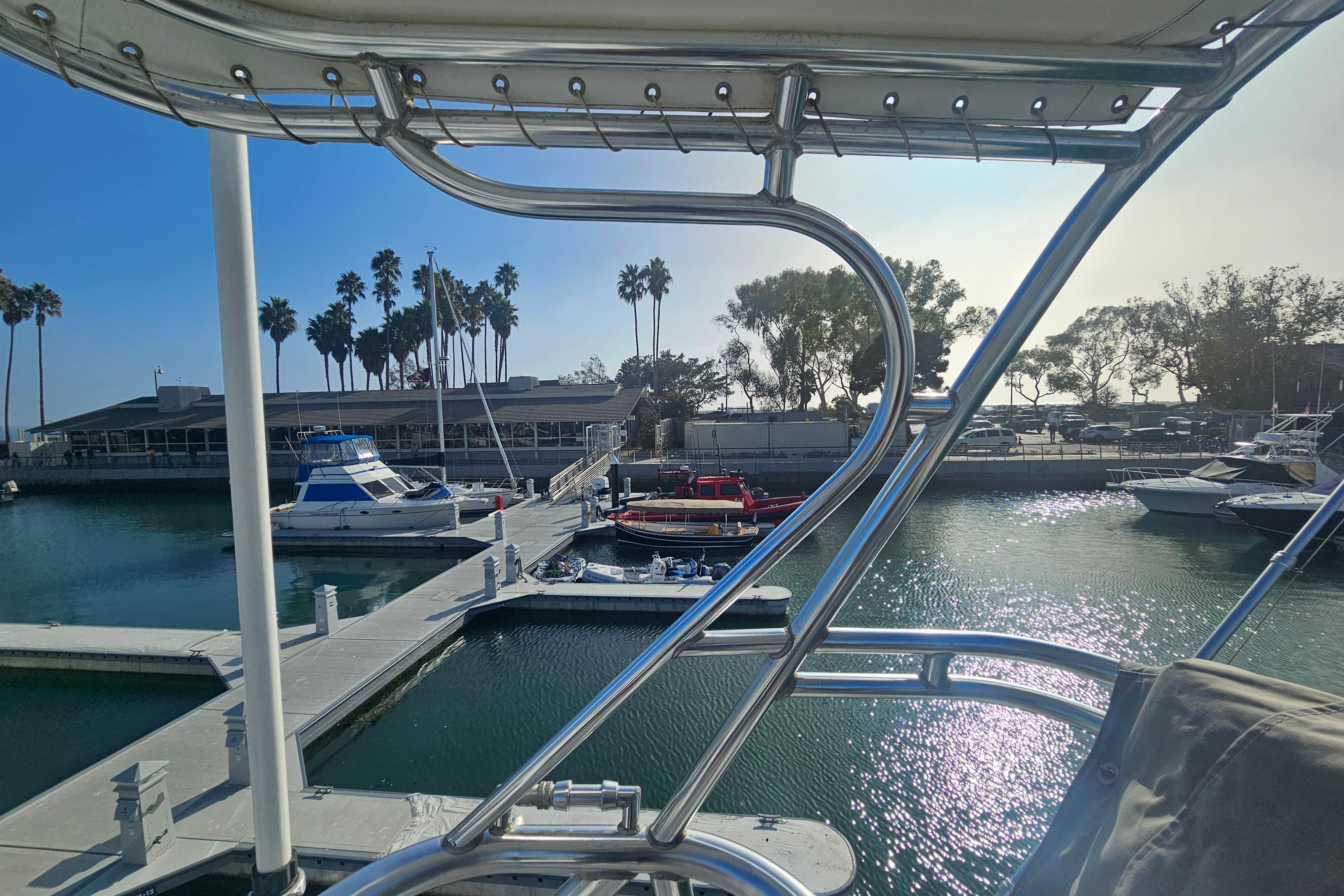 Marina view from 2003 Topaz 32 Express boat, featuring docked vessels and palm trees.