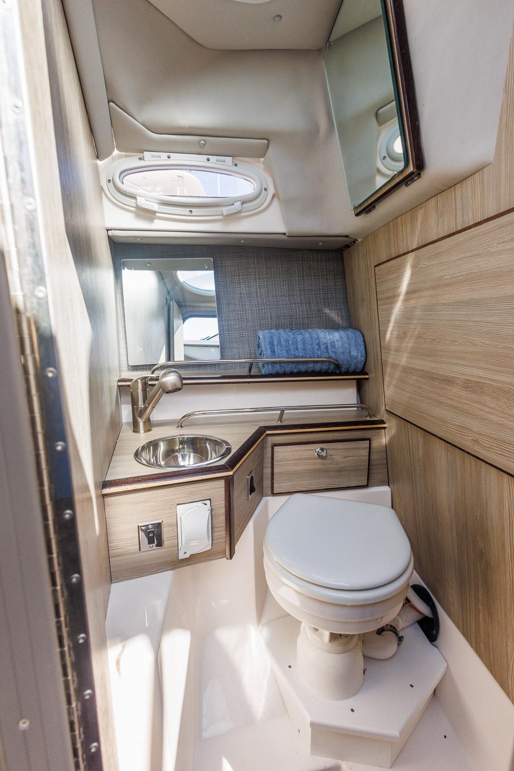 Modern bathroom in 2026 Solara 250-C boat with sink, toilet, and mirror.