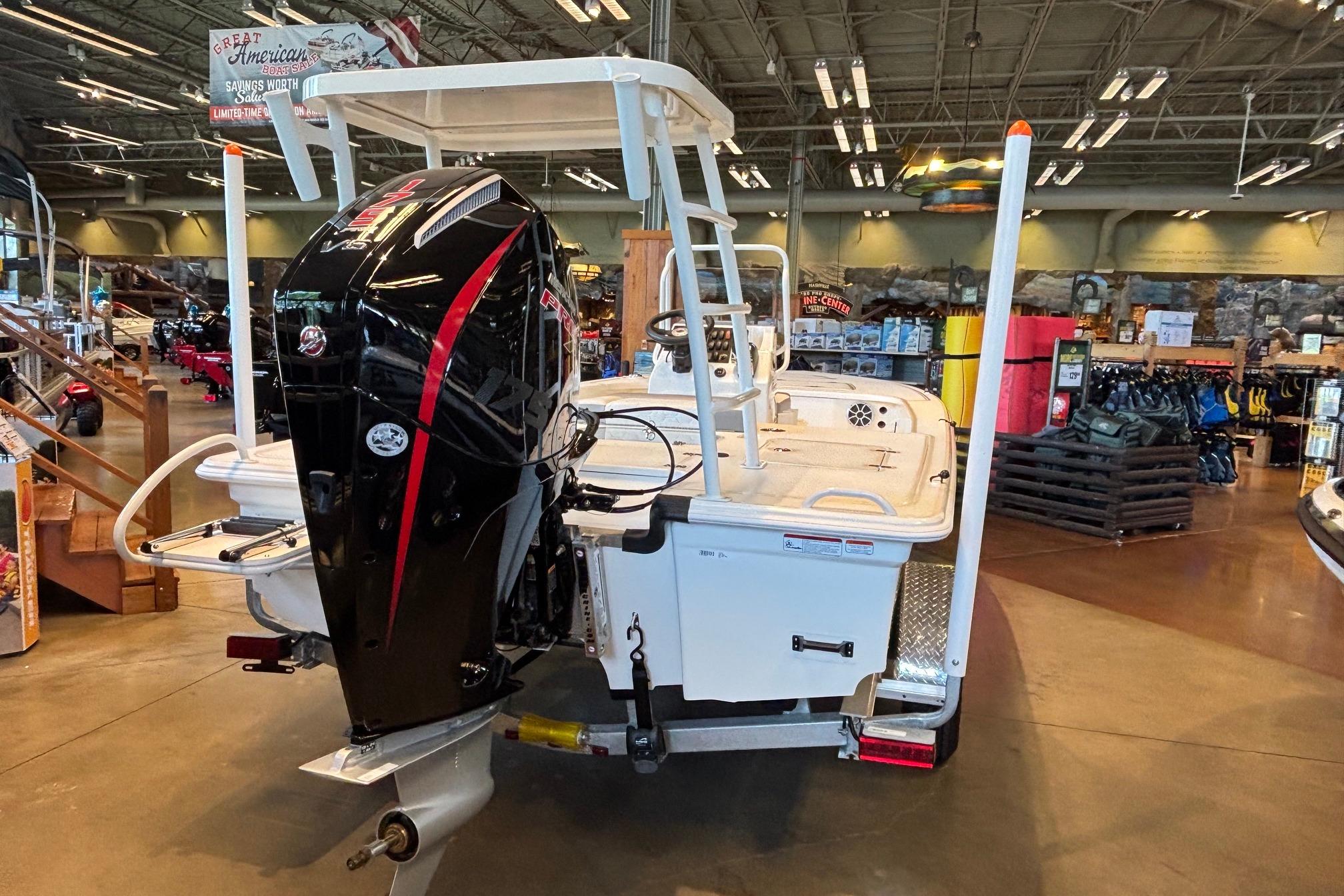 2026 Mako 18 Pro Skiff boat displayed indoors with powerful outboard motor.