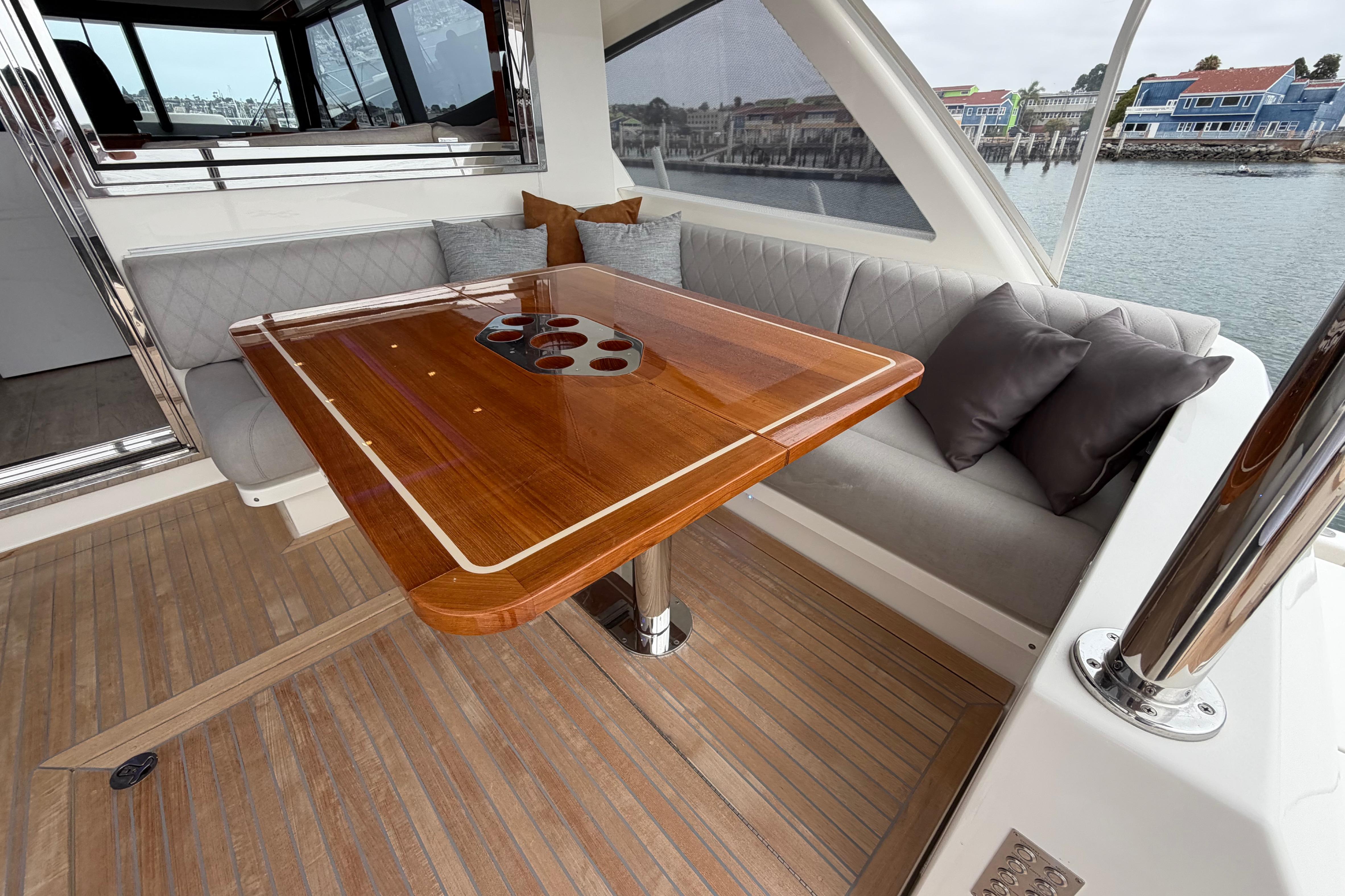 Luxurious interior of 2023 Riviera 645 SUV yacht with elegant wooden table and cushioned seating.