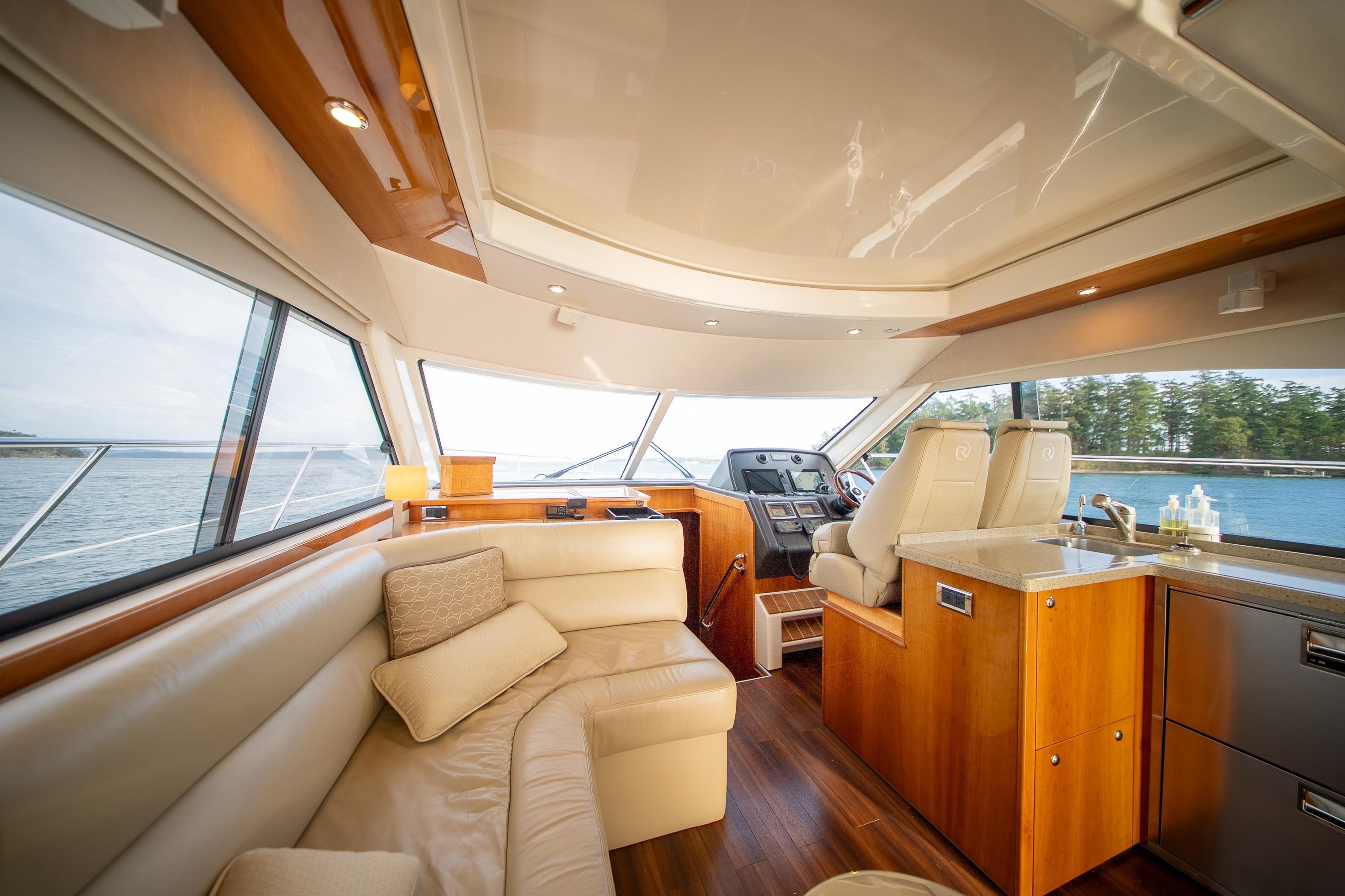 Luxurious interior of 2011 Riviera 5000 Sport Yacht with leather seating and modern helm.