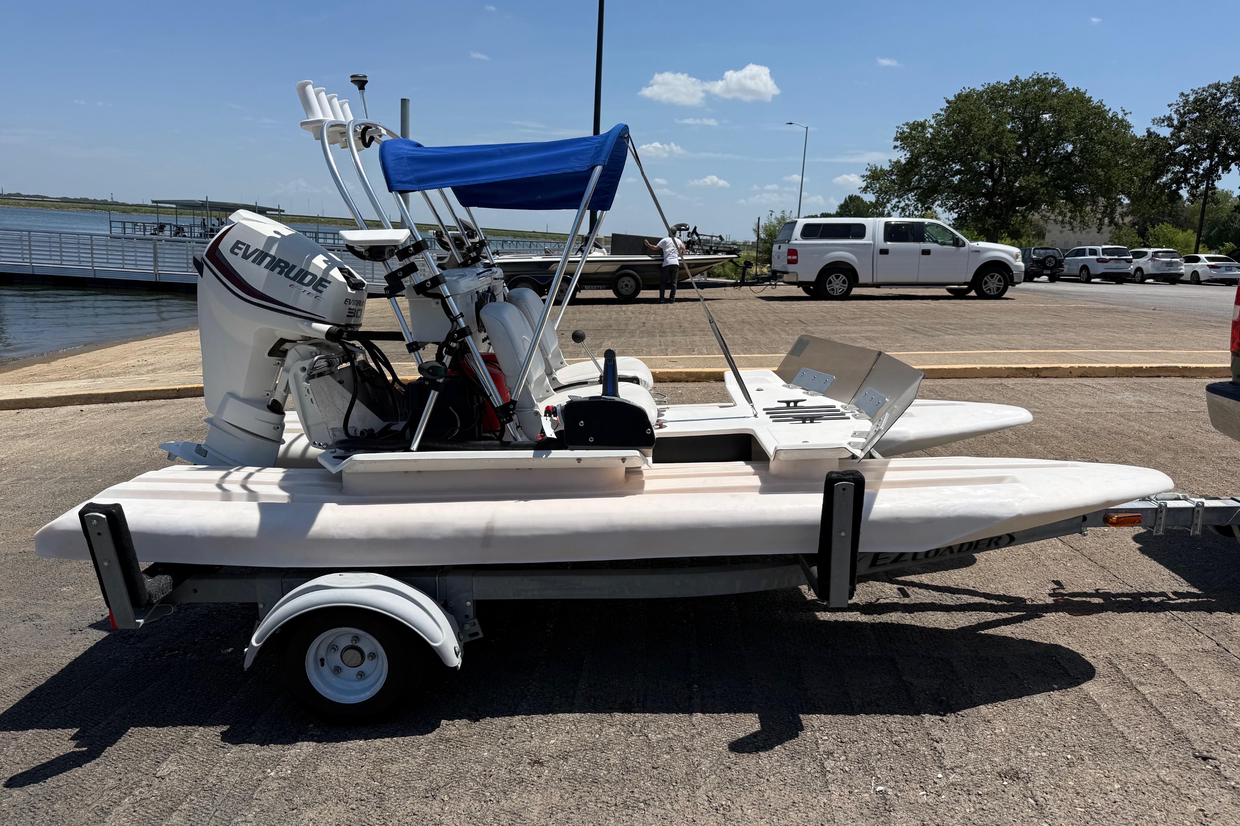 2016 CraigCat E2 Elite catamaran with Evinrude motor on a trailer at a lakeside dock.