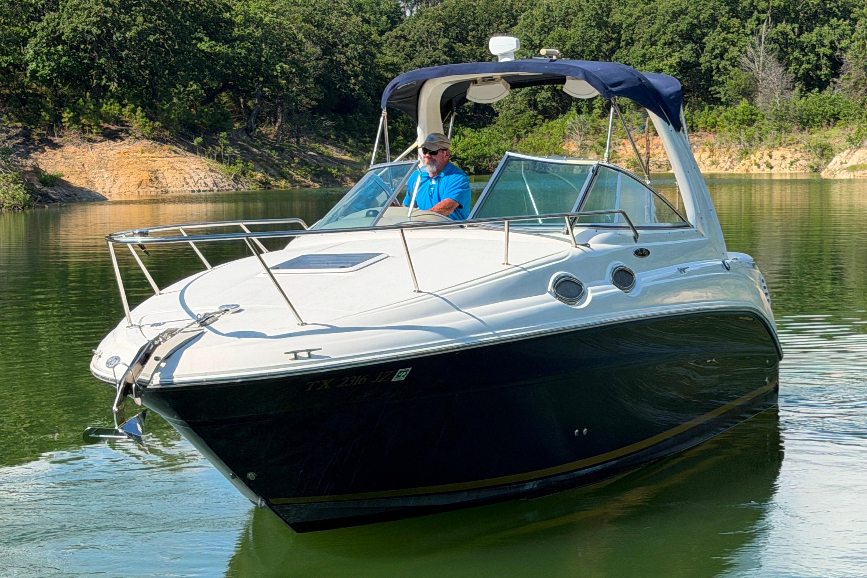 2004 Sea Ray Sundancer 260 cruising on a serene lake with lush greenery.