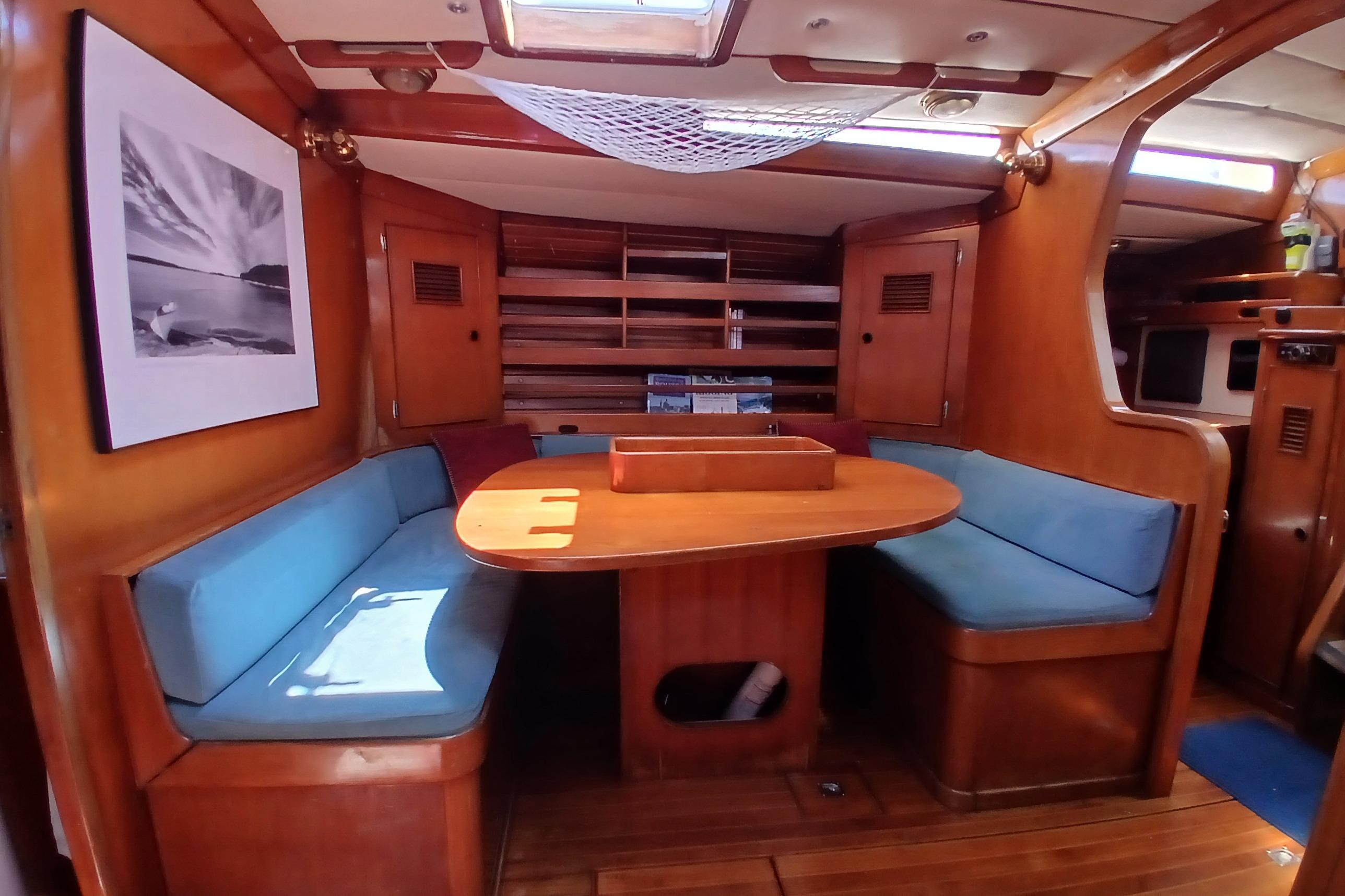 Interior of 1981 SKYE 51 yacht with wooden dining area and blue cushioned seating.