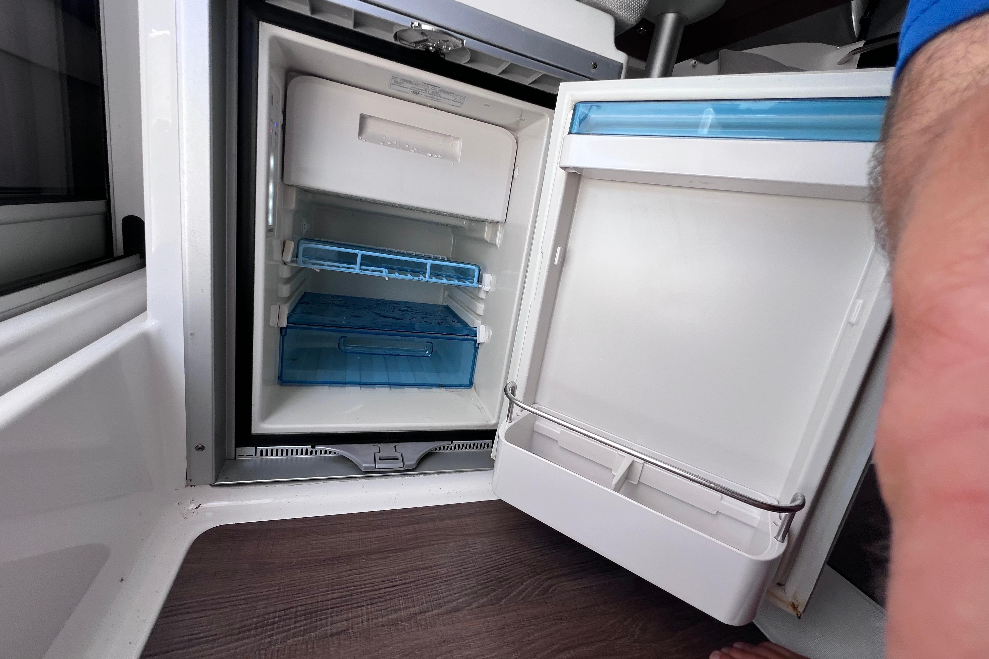 Open refrigerator inside 2021 Jeanneau NC Weekender 795 Series 2 boat, showcasing storage compartments.
