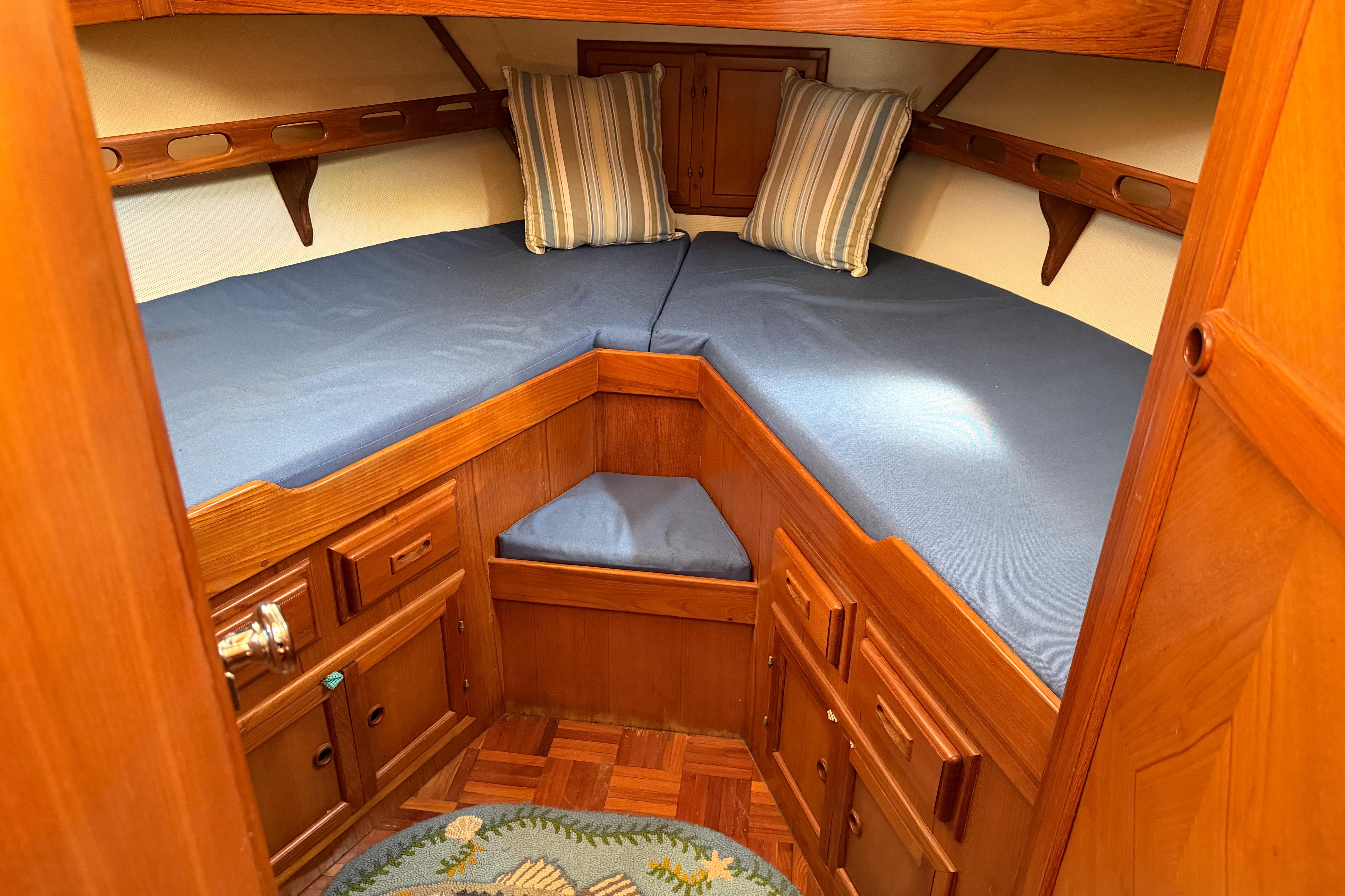 Cozy cabin interior of 1987 Marine Trader 36 with blue bedding and wooden cabinetry.