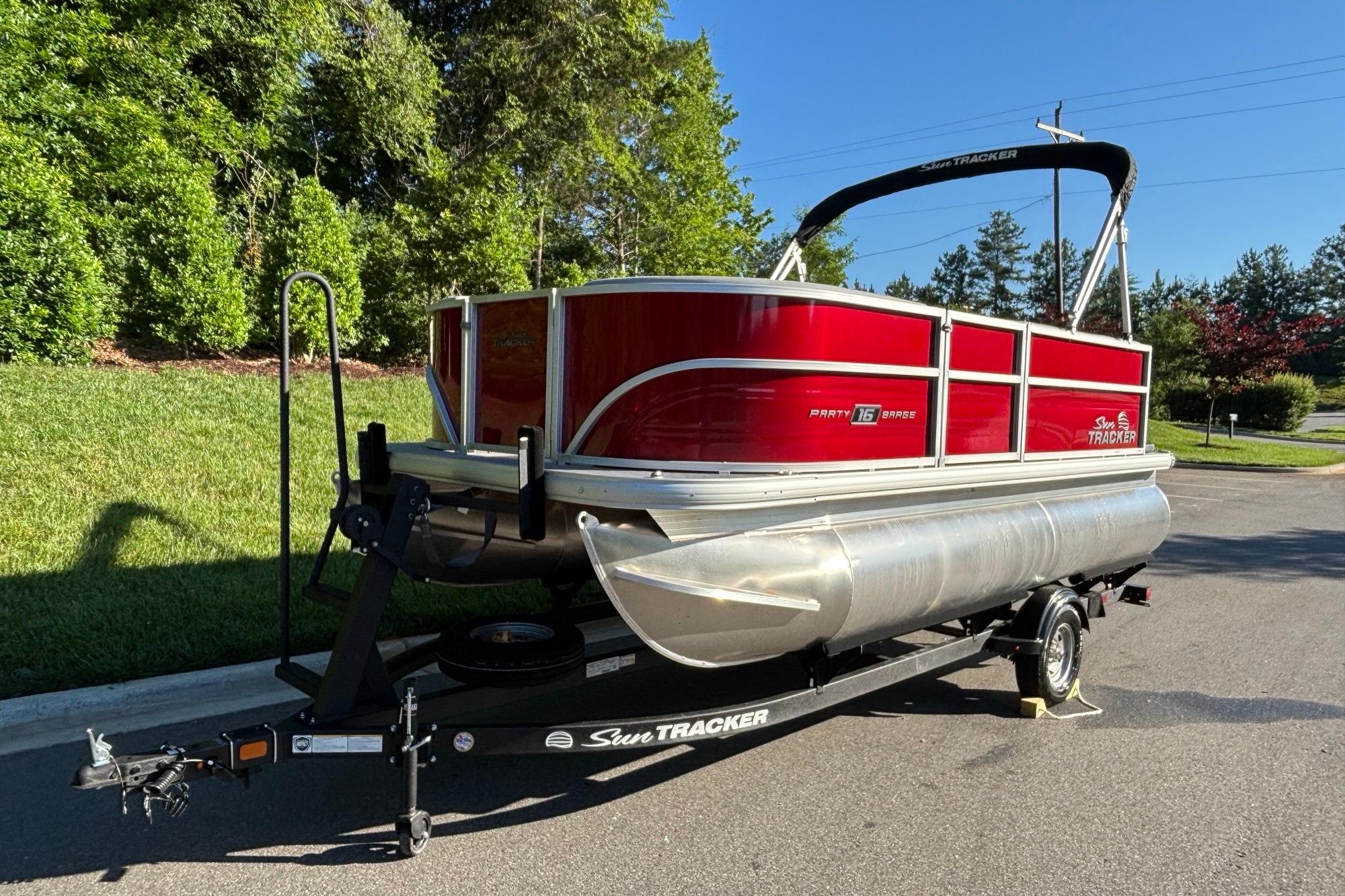 2026 Sun Tracker Party Barge 16 DLX pontoon boat on trailer, parked outdoors.