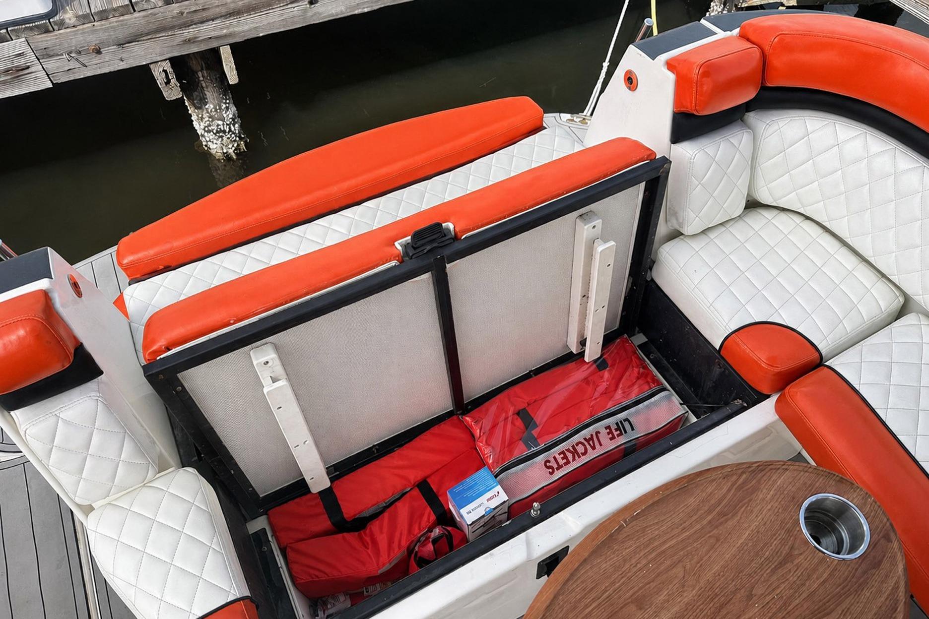 2012 Rinker 310 Express Cruiser LE with open storage, life jackets, and cushioned seating.