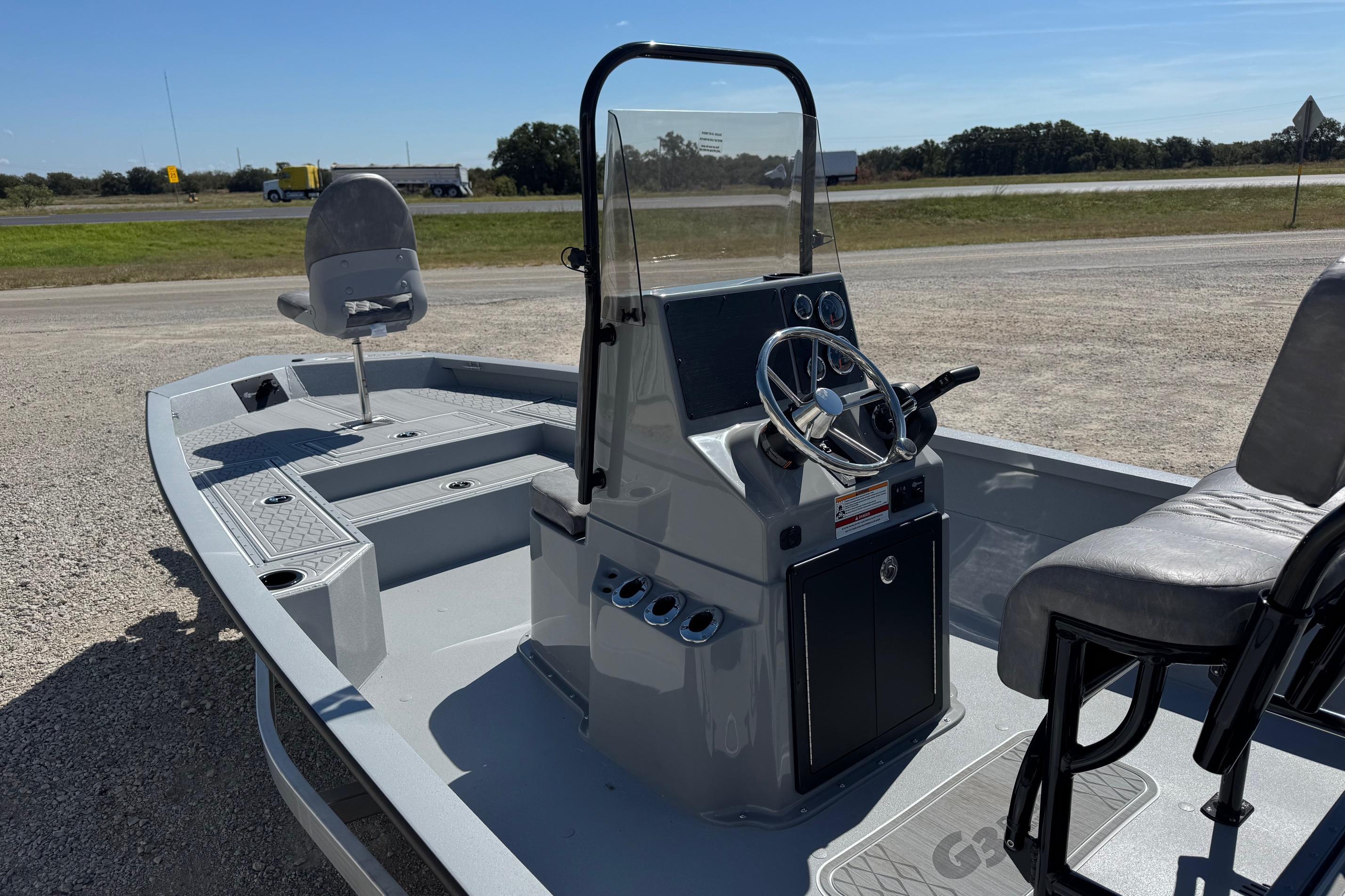 2026 G3 21GX boat with steering console and seating, parked on gravel near highway.