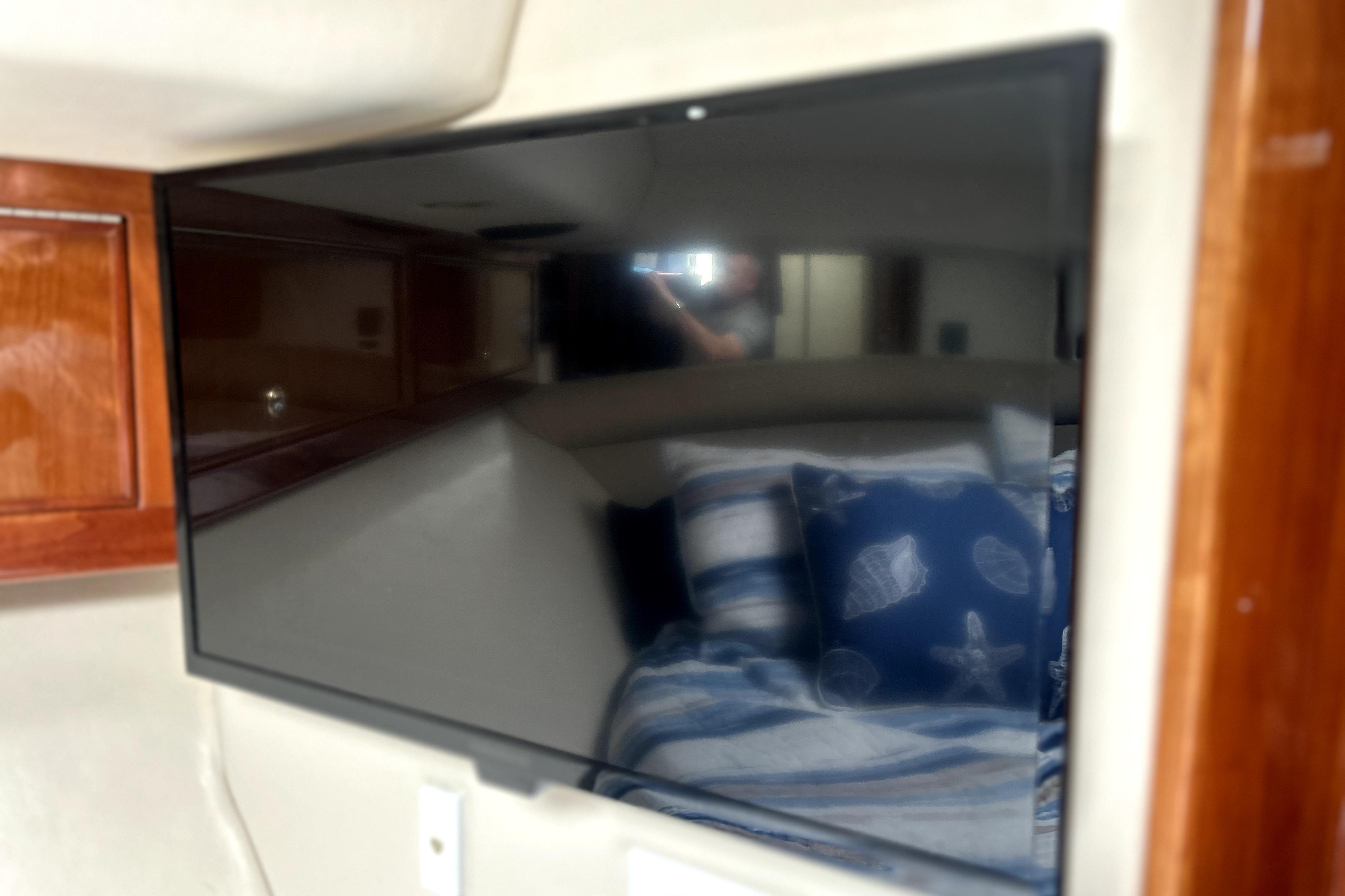 Interior of 2004 Wellcraft 47 Excalibur with TV and nautical-themed bedding.