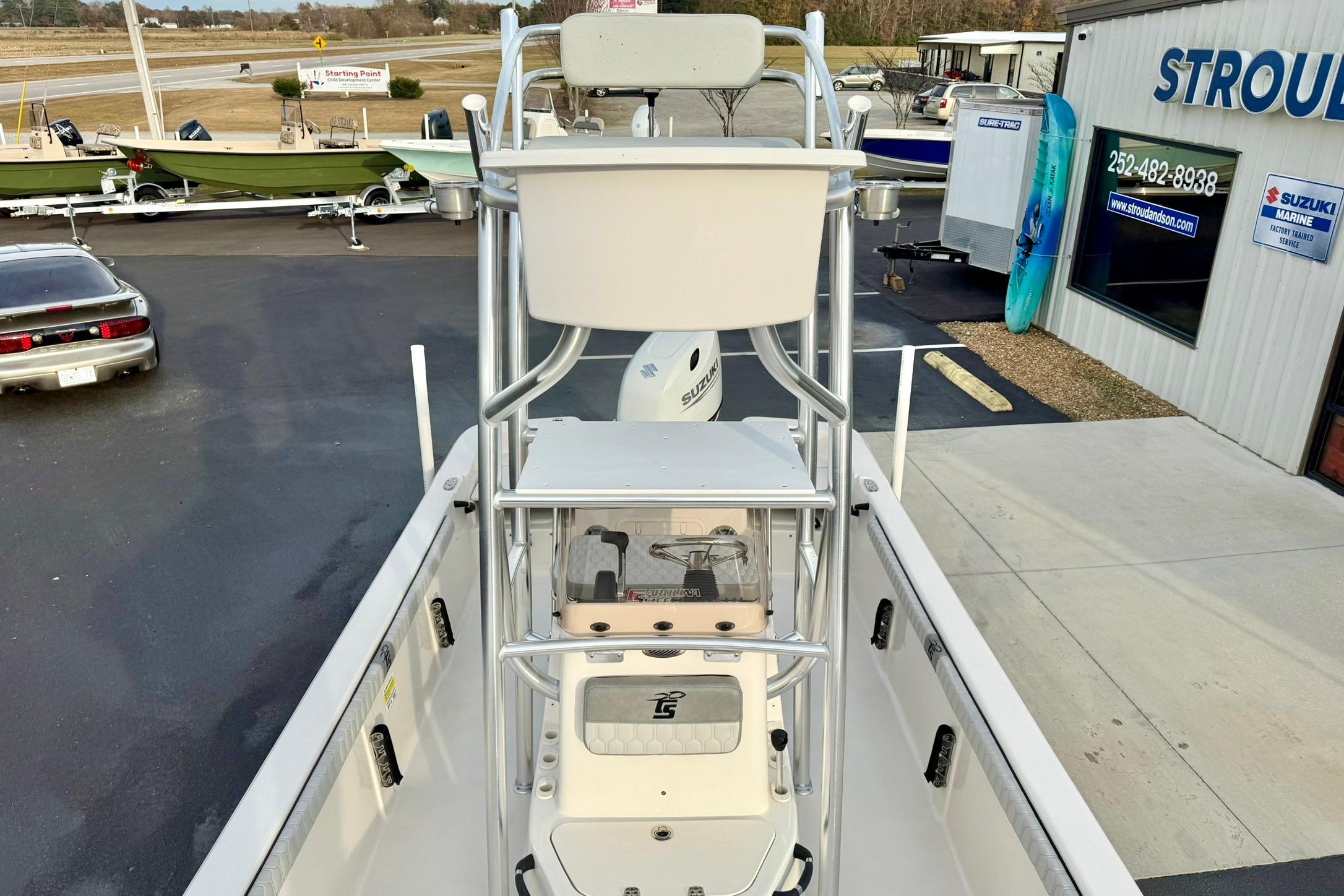 2025 Carolina Skiff 21 LS boat at dealership, featuring elevated seating and Suzuki engine.