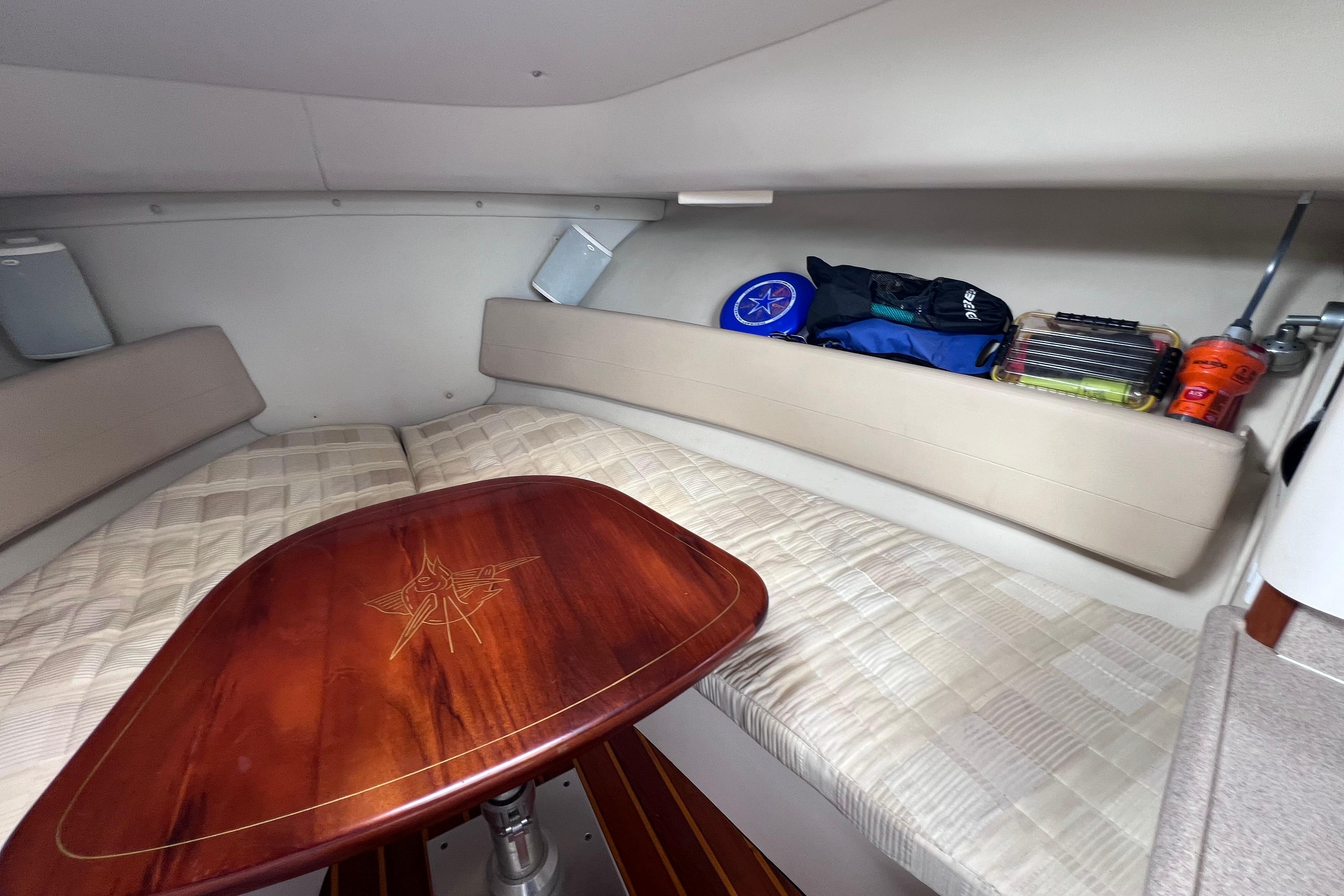 2005 Pursuit 3070 Offshore cabin interior with cushioned seating and wooden table.