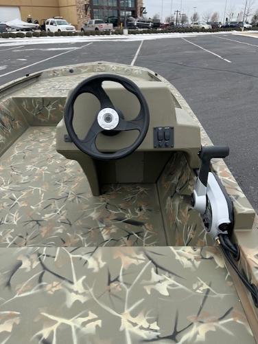 2025 Tracker Grizzly 1648 SC boat with camouflage interior in a parking lot.