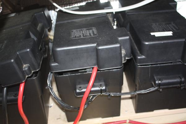Batteries in a boat with cables and black casings.