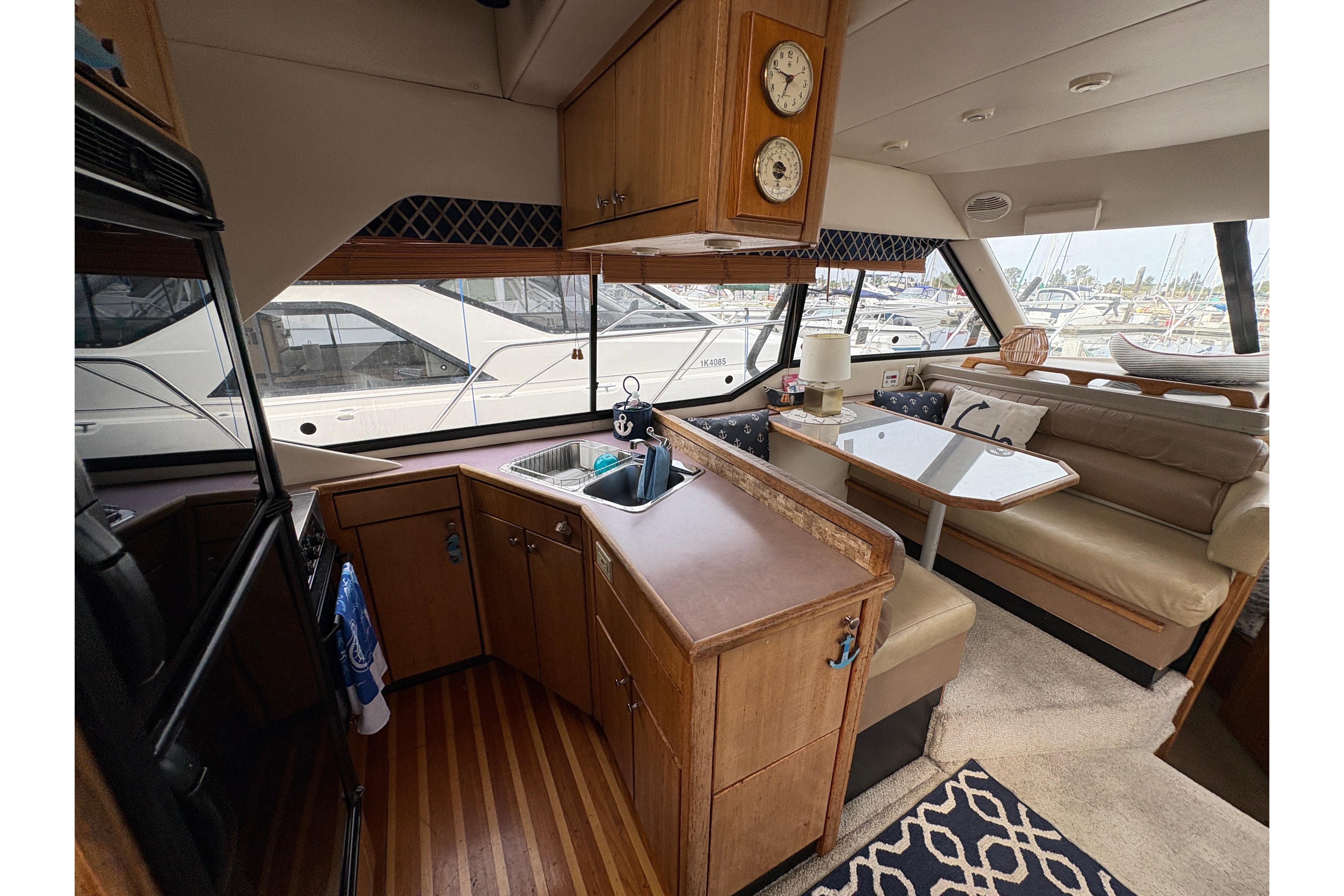 1988 Bayliner 3587 Motoryacht interior with kitchen and dining area, featuring wood cabinetry and seating.