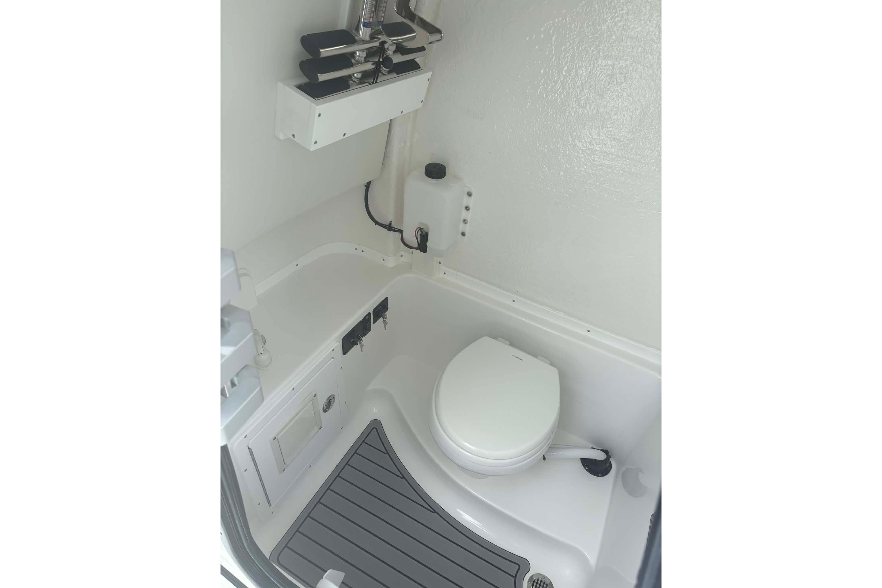 Interior of 2026 Tidewater 282 CC Adventure boat featuring a compact marine toilet.