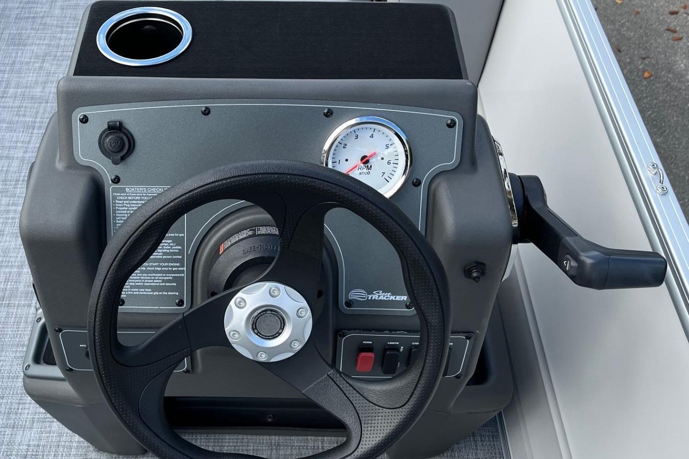 Steering console of 2026 Sun Tracker Party Barge 16 DLX with RPM gauge and cup holder.
