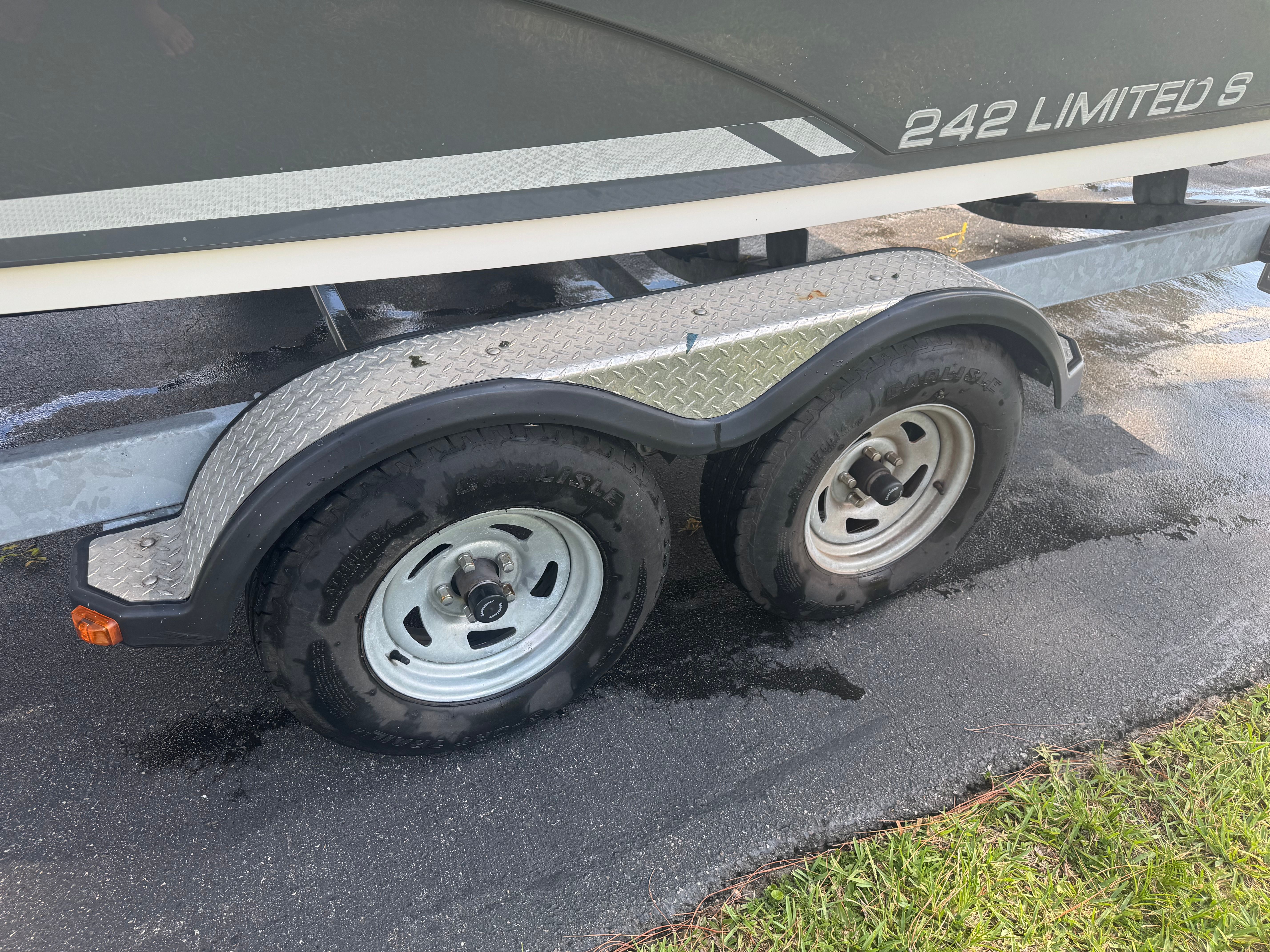 The 2015 Yamaha 242 Limited S is on a trailer with two tires.