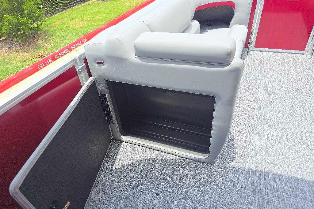 2026 Sun Tracker Party Barge 20 DLX interior with open storage compartment and gray seating.